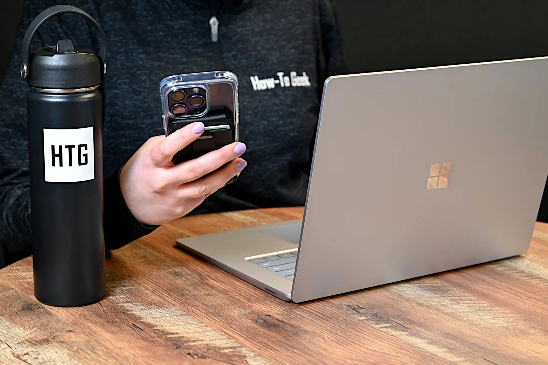 Điện thoại iPhone và laptop Windows trên bàn làm việc, thể hiện sự đa dạng lựa chọn thiết bị công nghệ hiện nay.