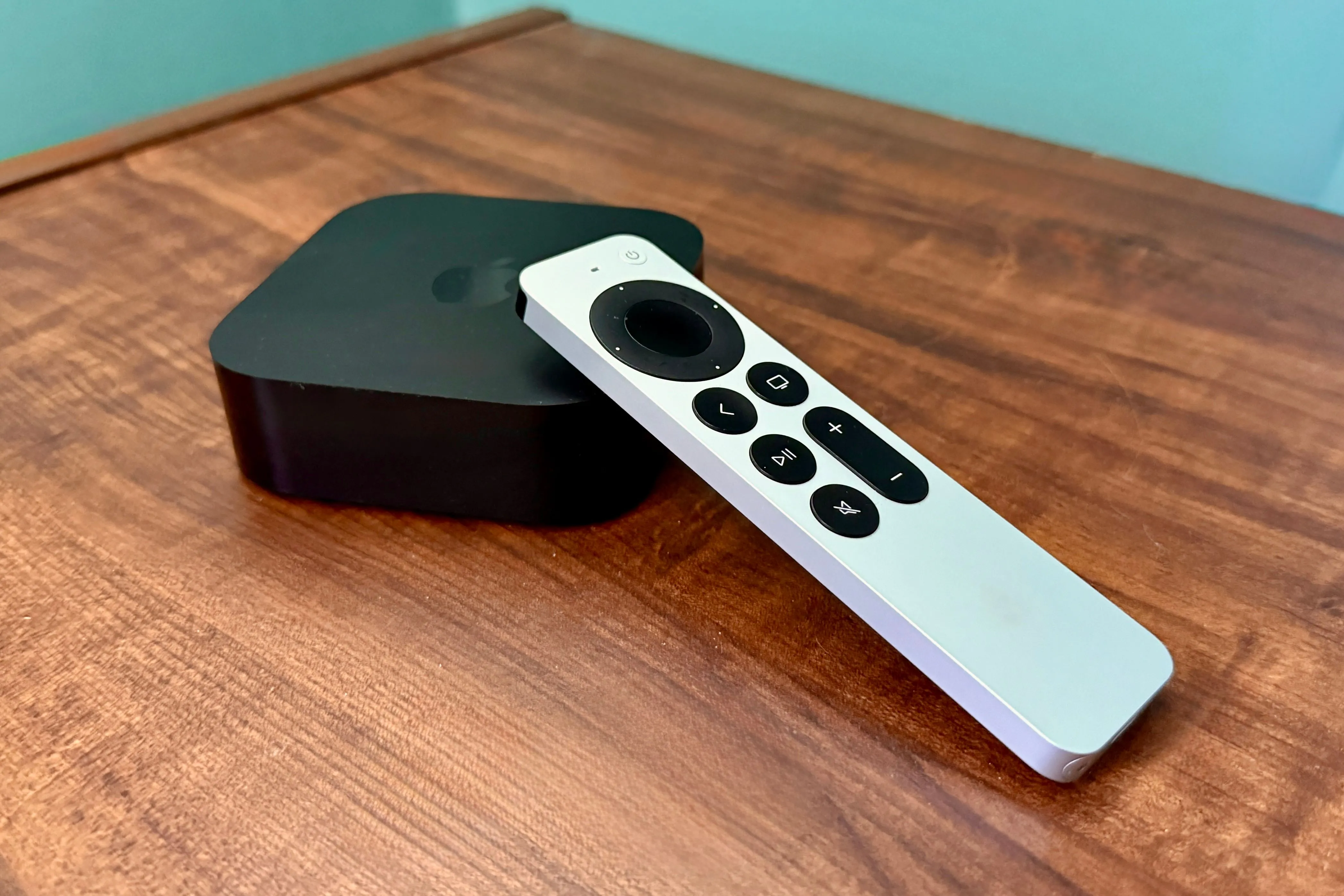 Hình ảnh Apple TV 4K và remote Siri trên bàn gỗ, biểu tượng của hệ sinh thái giải trí Apple
