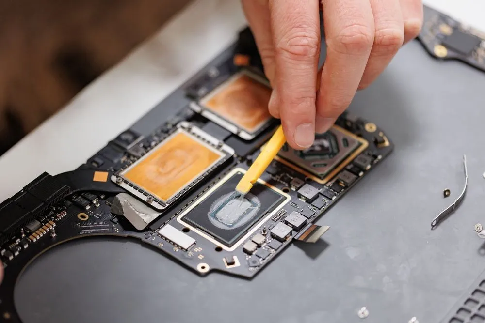 Kỹ thuật viên đang tỉ mỉ sửa chữa bên trong một chiếc MacBook, nhấn mạnh chi phí nhân công