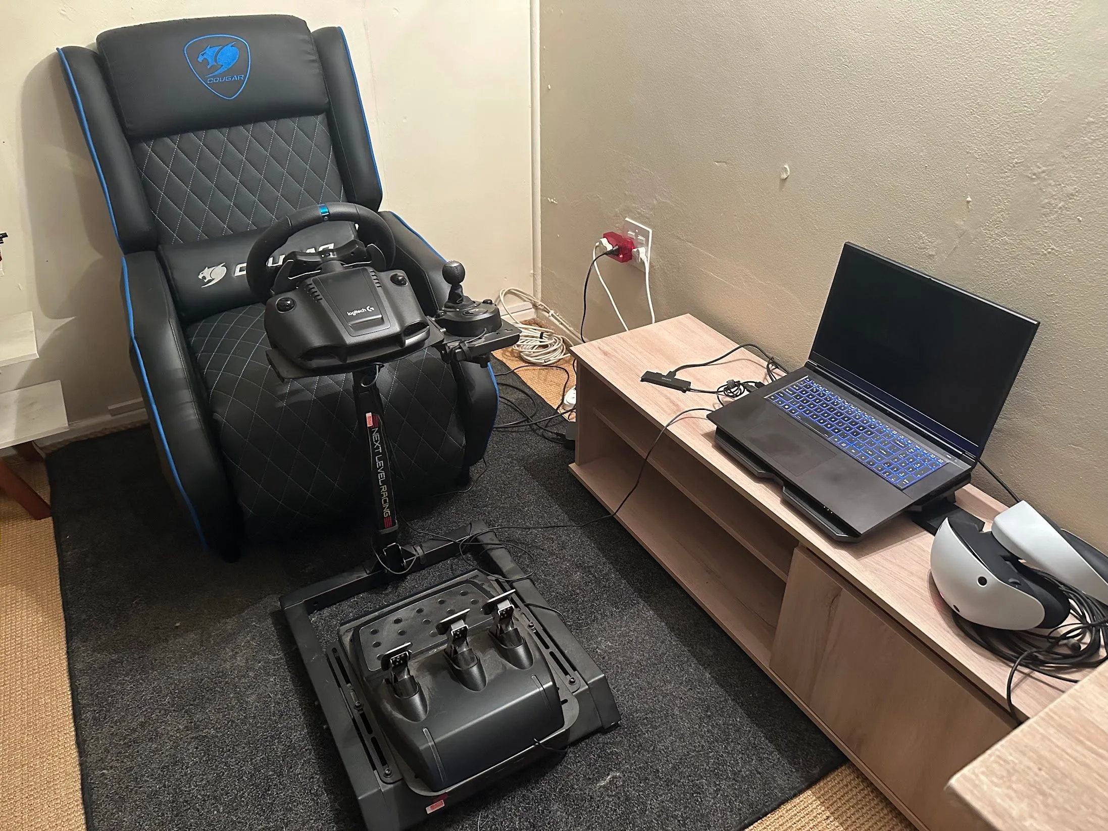 Laptop gaming được đặt cạnh kính VR và bộ điều khiển đua xe, tối ưu không gian giải trí
