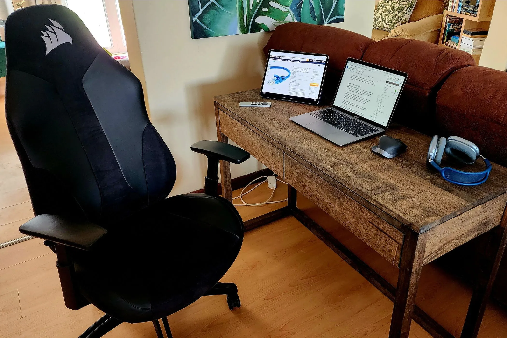Một bàn làm việc với MacBook và iPad đặt cạnh nhau, cùng với AirPods Max và điều khiển Apple TV, thể hiện hệ sinh thái liền mạch của Apple.