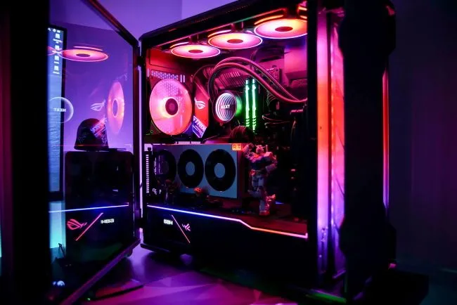Một chiếc PC gaming với tấm kính bên cạnh đã được mở, để lộ ánh sáng RGB rực rỡ bên trong, tượng trưng cho niềm tự hào và sự hài lòng sau khi hoàn thành việc lắp ráp.