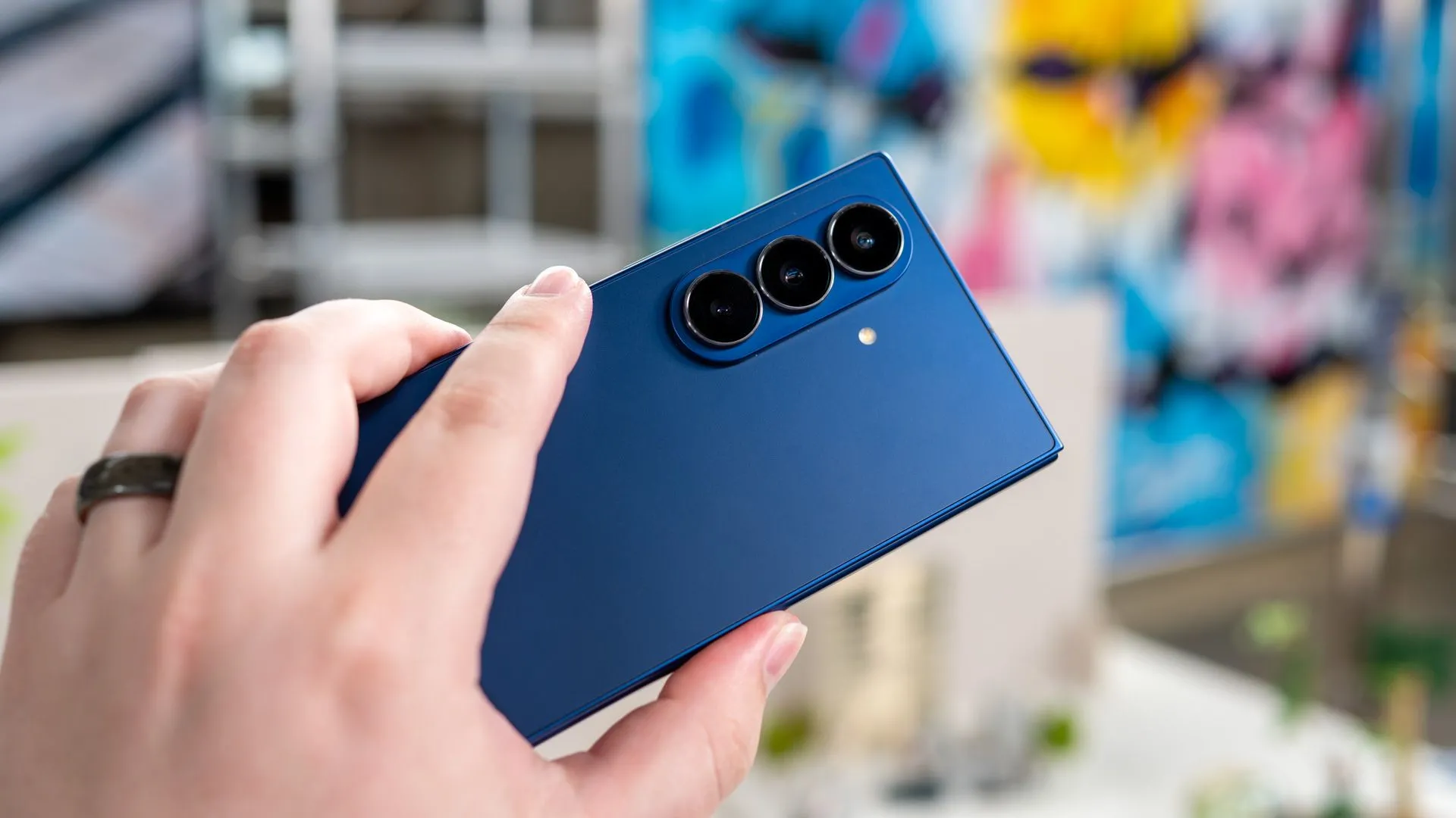 Một người đang cầm Samsung Galaxy Z Fold 7 mở ra, hiển thị mặt lưng và cụm camera 200MP, làm nổi bật hệ thống camera tiên tiến của điện thoại gập này.