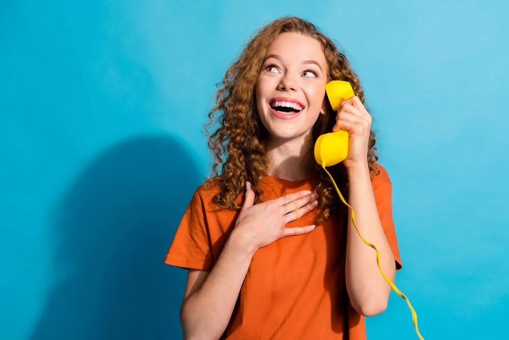 Một người phụ nữ đang cầm điện thoại bàn màu vàng kiểu cũ