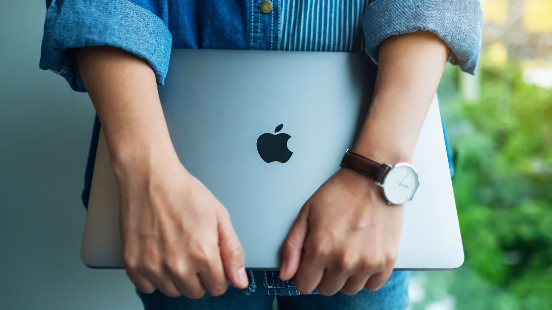 Một người phụ nữ tự tin cầm chiếc MacBook Pro, tượng trưng cho chiến lược thương hiệu cao cấp của Apple