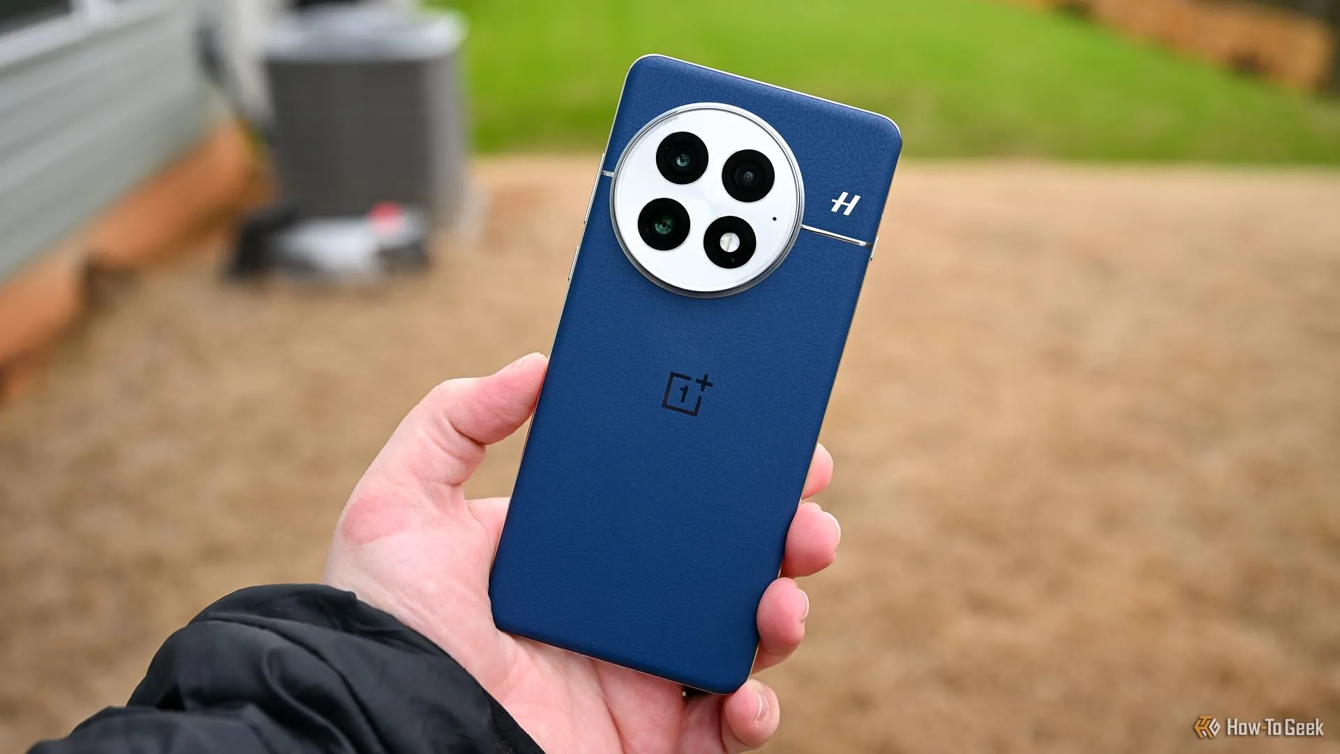 Người dùng cầm OnePlus 13 màu xanh, thể hiện thiết kế và cụm camera, minh họa pin silicon-carbon.