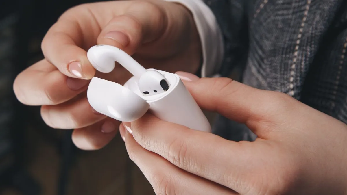Người dùng lấy AirPods ra khỏi hộp sạc, nhắc nhở về tầm quan trọng của việc vệ sinh tai nghe.
