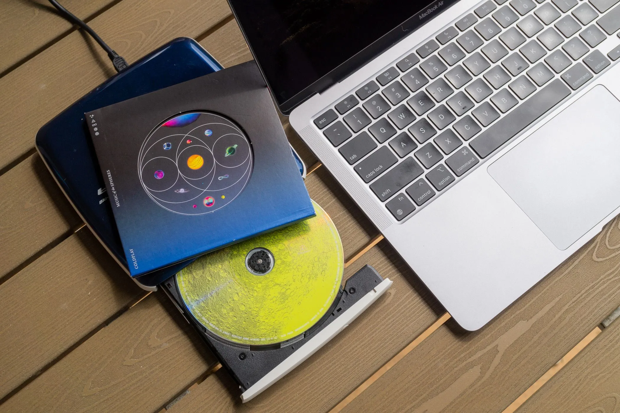 Ổ đĩa CD và một đĩa CD nhạc bên cạnh MacBook Air.
