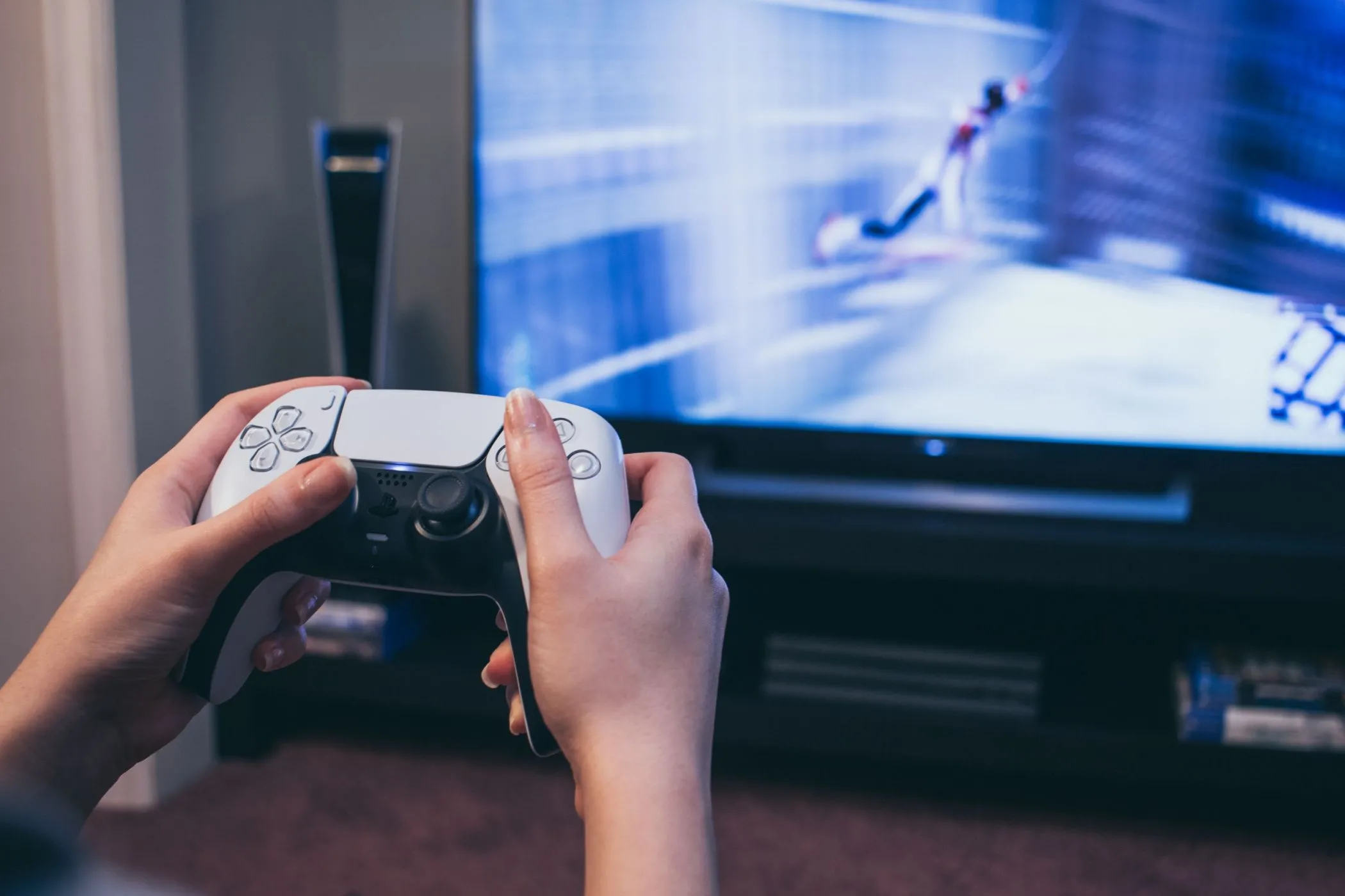 Tay cầm DualSense PS5 với hình ảnh game Spider-Man trên TV, minh họa tính năng chia sẻ game