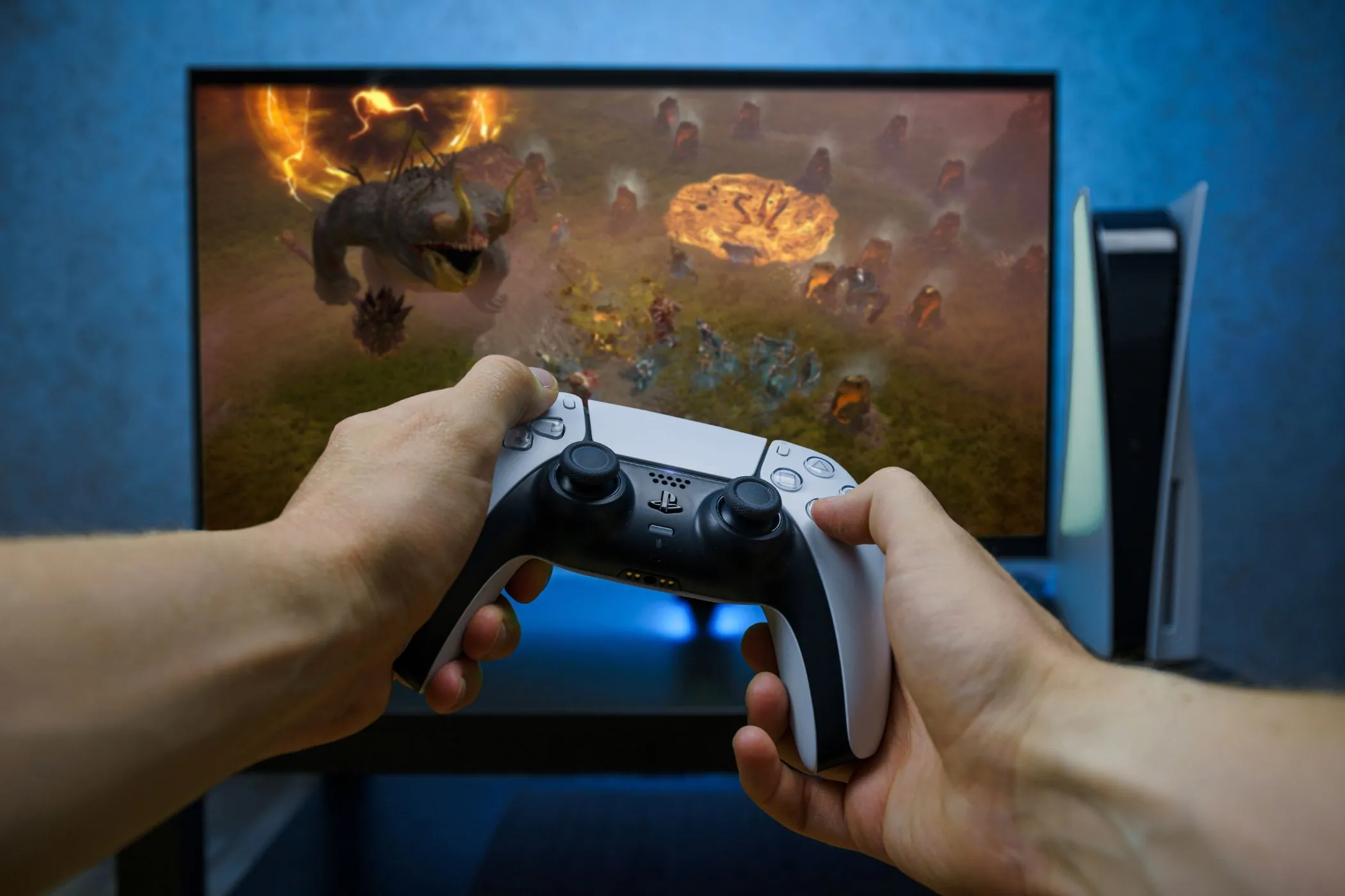 Tay cầm PlayStation 5 đặt trước màn hình gaming, minh họa khả năng kết nối console cho mục đích giải trí
