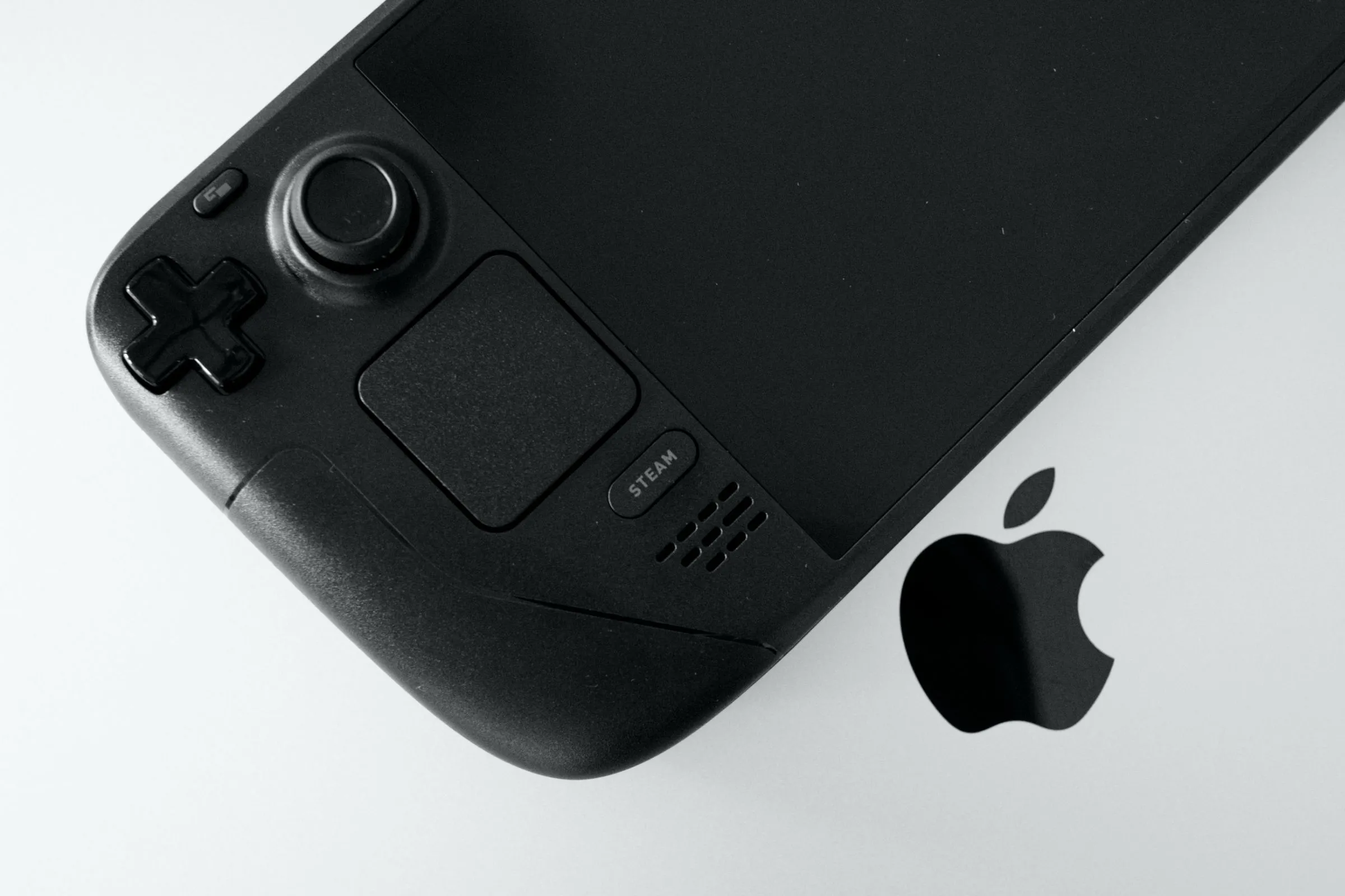 Thiết bị chơi game cầm tay Steam Deck OLED đặt cạnh MacBook Pro minh họa việc điều khiển từ máy tính