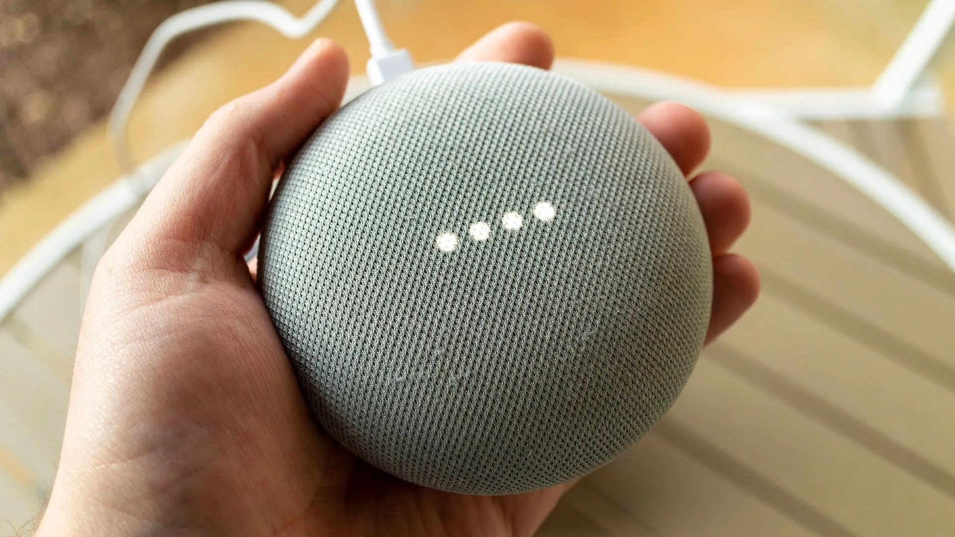 Bàn tay đang cầm loa Google Nest, thể hiện khả năng điều khiển thiết bị thông minh qua trợ lý giọng nói