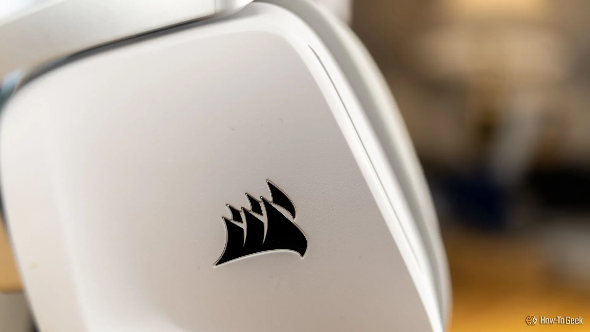 Cận cảnh logo CORSAIR trên vành tai nghe Corsair Void Wireless V2 màu trắng, nổi bật với thiết kế hiện đại.