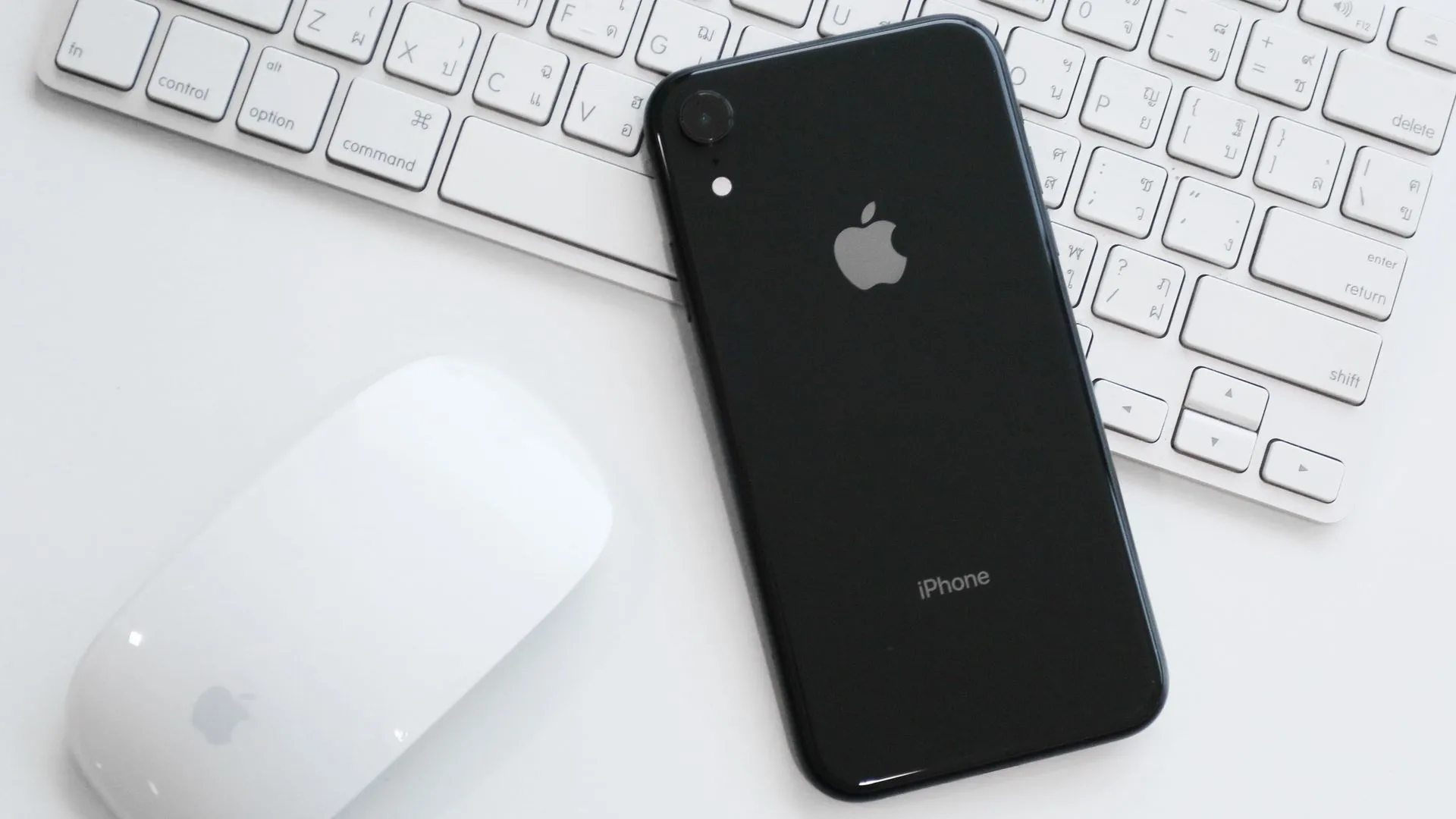 Chiếc iPhone XR với camera đơn trên bàn làm việc cùng Magic Mouse và Magic Keyboard, biểu tượng của sự tinh giản và hiệu quả.