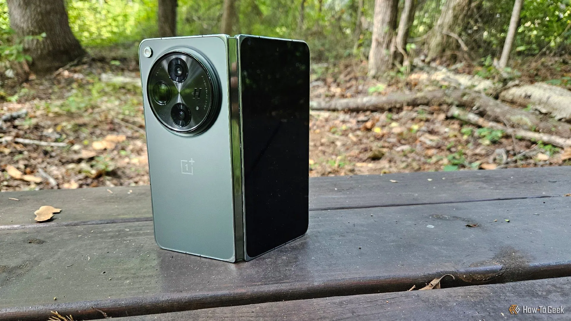 Điện thoại OnePlus Open đặt thẳng đứng trên ghế đá.