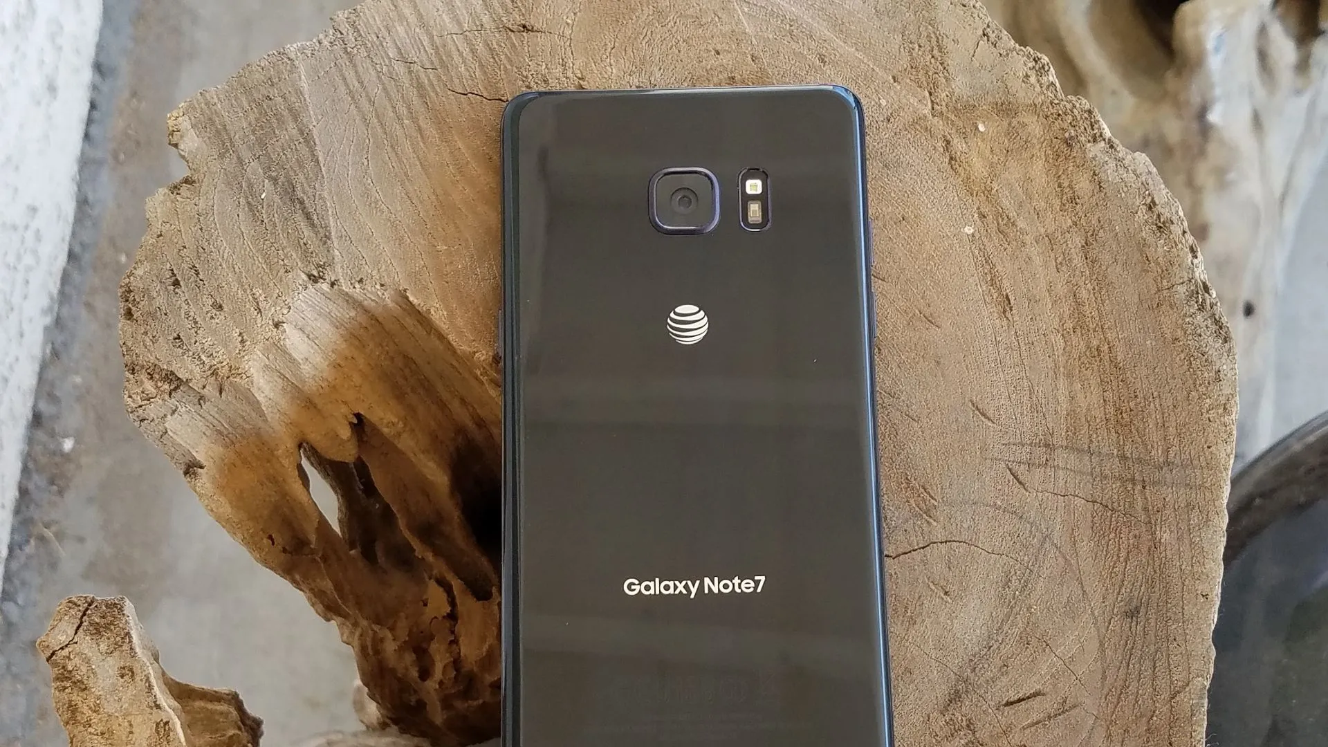 Điện thoại Samsung Galaxy Note 7 màu đen đặt trên một khối gỗ, làm nổi bật thiết kế cong đặc trưng của màn hình