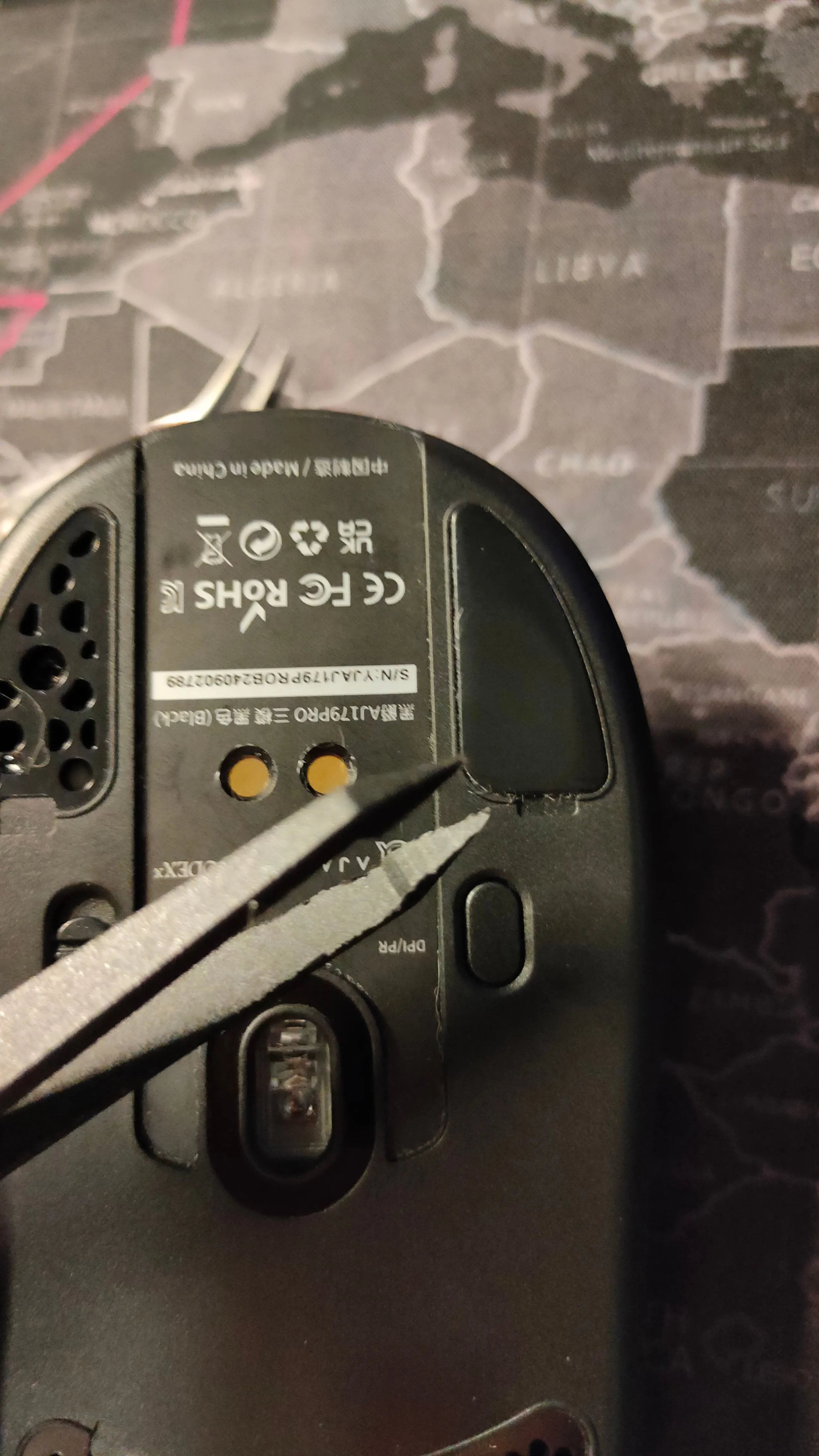 Hình ảnh cận cảnh một người dùng đang cẩn thận gỡ mouse skates cũ bằng nhíp, cho thấy quy trình tháo dỡ.