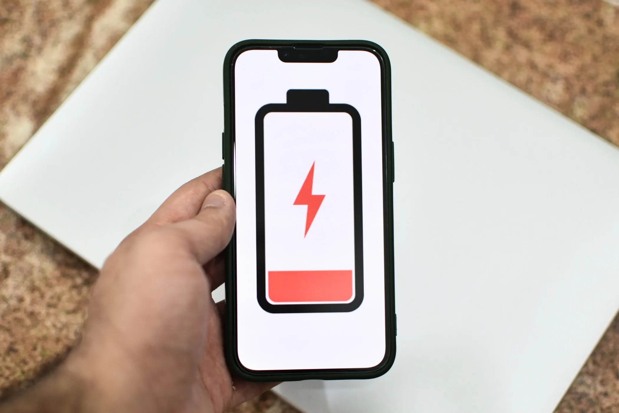 Hình minh họa chiếc iPhone với biểu tượng pin yếu trên màn hình, cảnh báo về tình trạng hao pin.