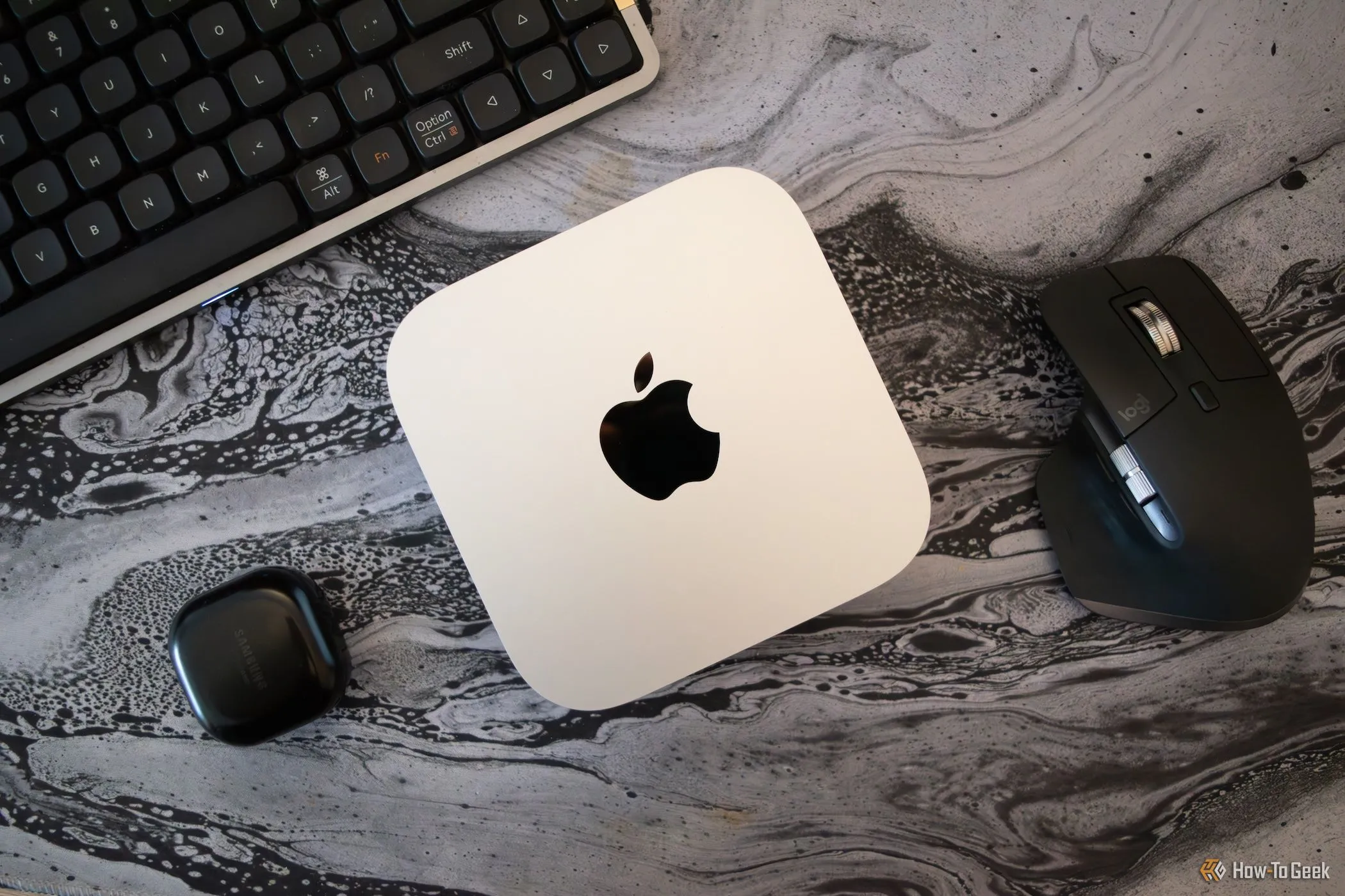 Mac Mini M4 đặt trên bàn làm việc cùng các thiết bị ngoại vi PC khác như bàn phím và chuột