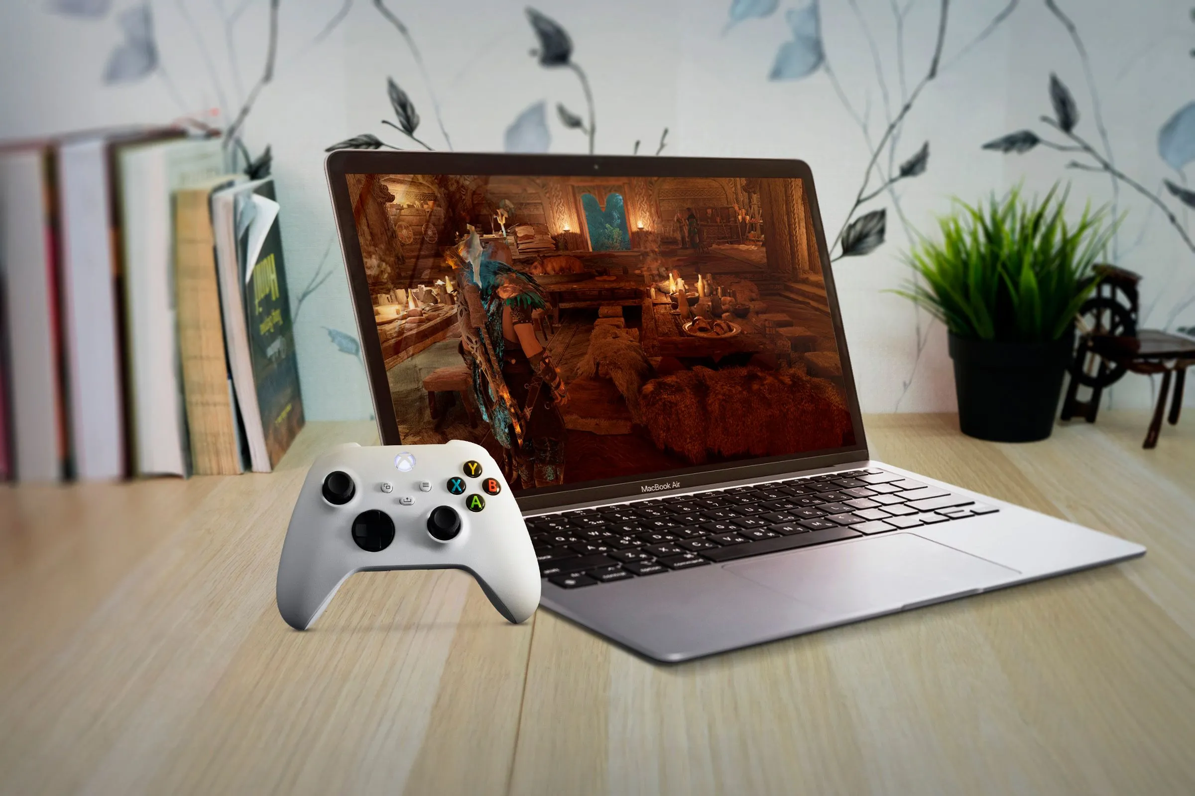 Một chiếc MacBook Air đang hiển thị trò chơi trên màn hình, với tay cầm Xbox ở gần, minh họa tiềm năng gaming nếu Apple phát triển công cụ hỗ trợ cho Mac
