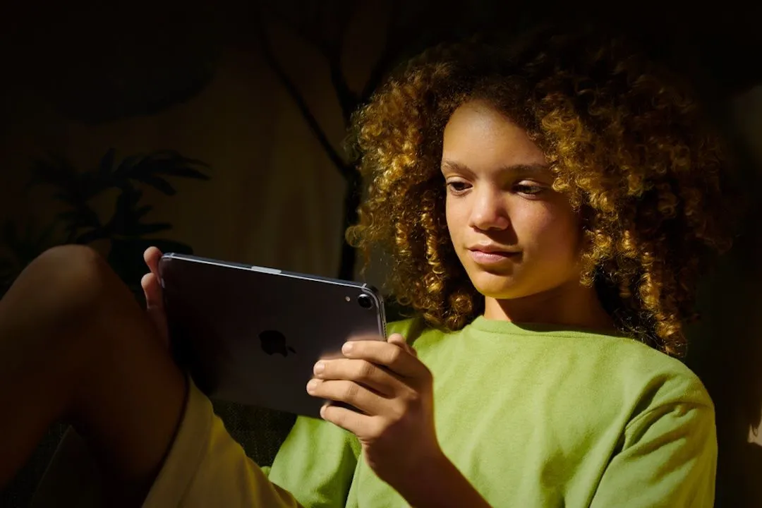 Một đứa trẻ đang sử dụng iPad, thể hiện việc áp dụng giới hạn thời gian sử dụng màn hình cho thiết bị di động.