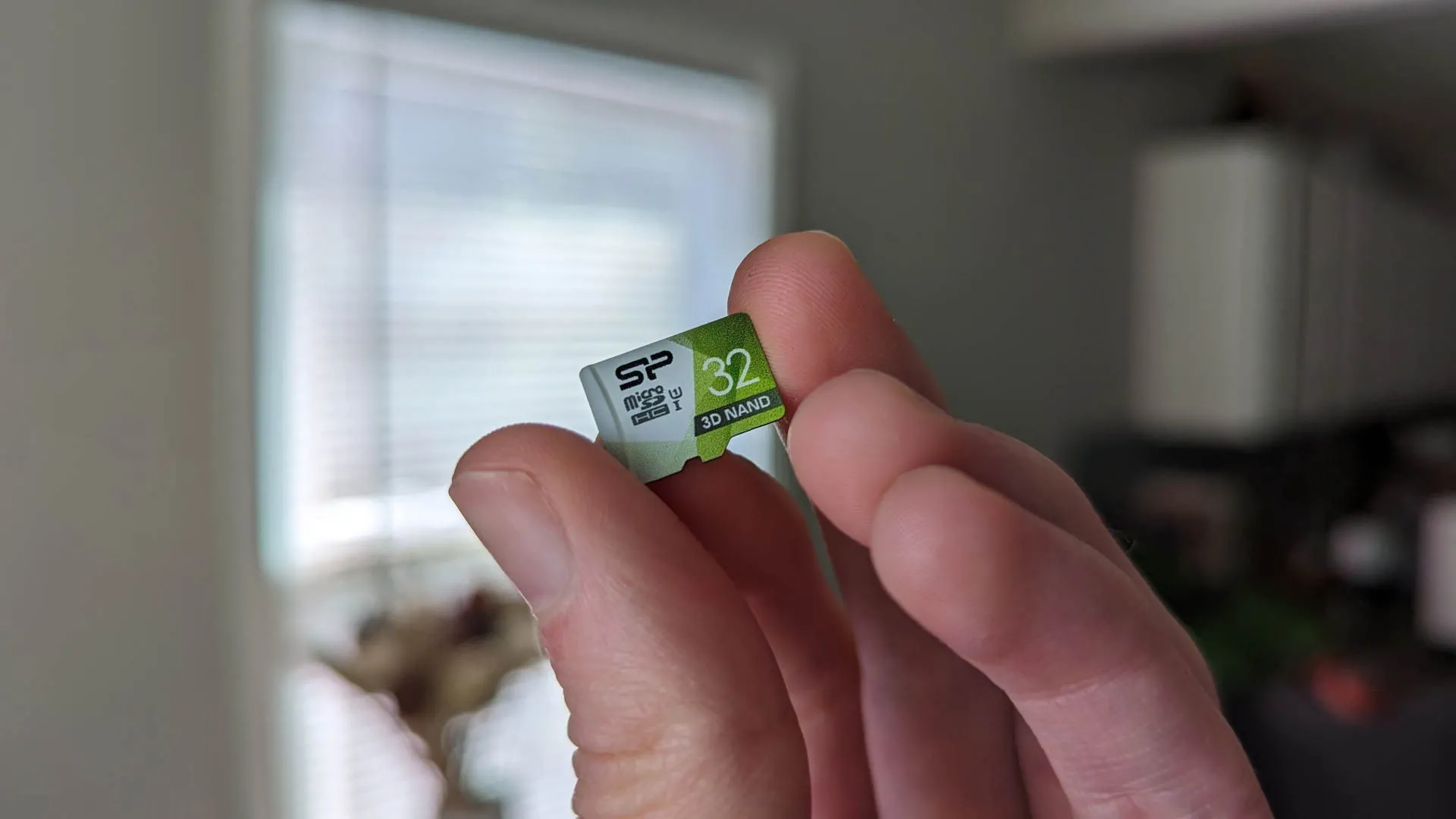 Một người đang cầm thẻ nhớ microSD nhỏ gọn giữa các ngón tay, thể hiện khả năng lưu trữ di động và tiện lợi.