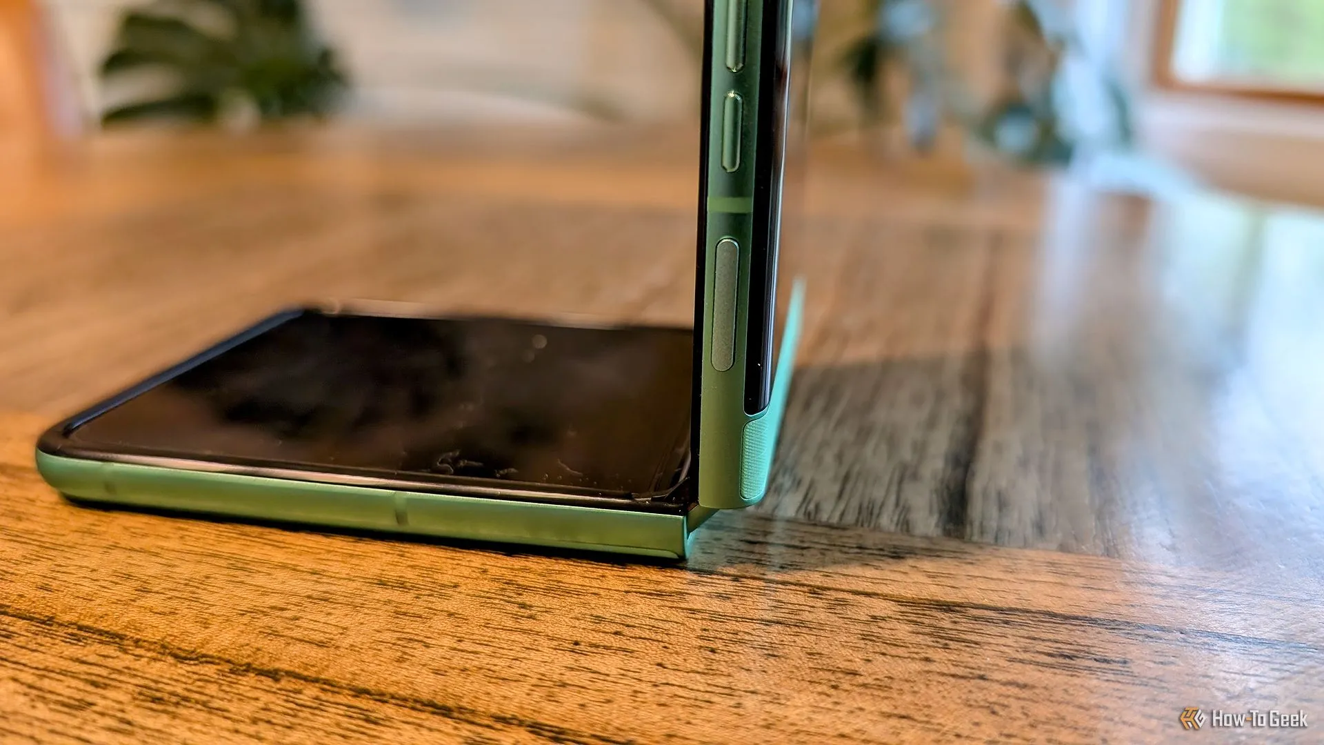 Moto Razr 2025 mở ra một nửa trên bàn, hiển thị màn hình chính và bản lề