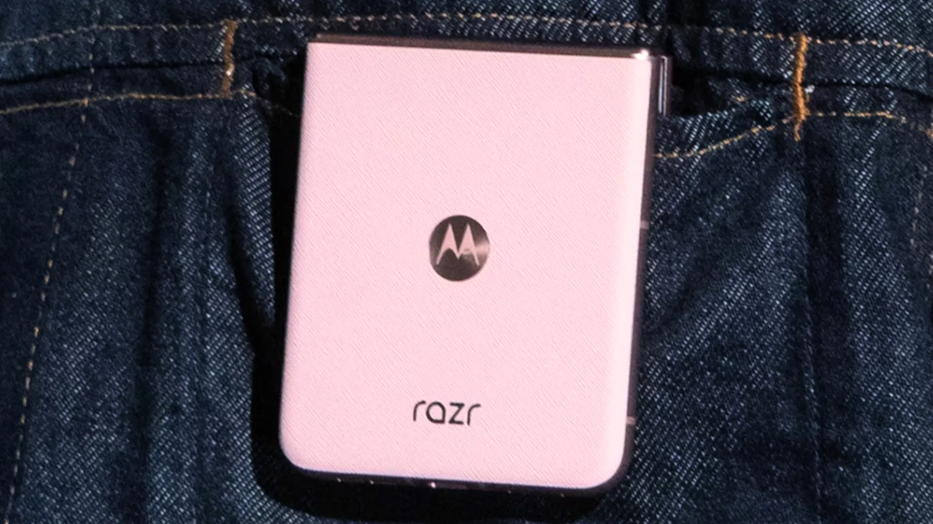 Motorola Razr 2025 màu hồng nhạt được cầm trên tay, hiển thị màn hình phụ.