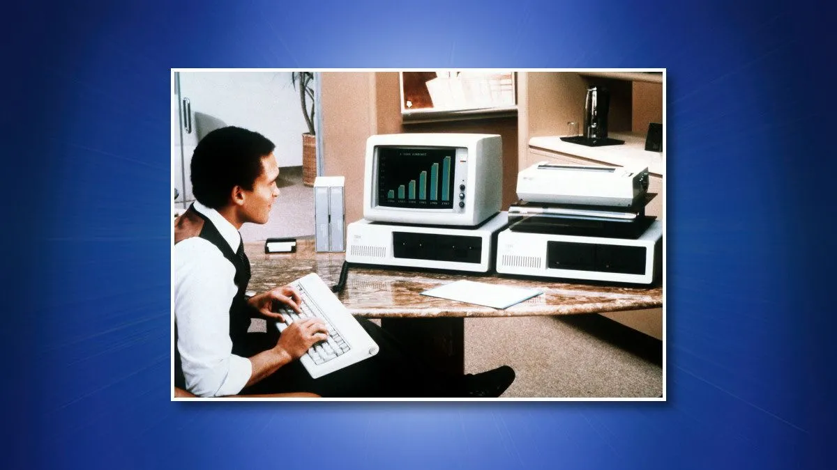 Người đàn ông sử dụng máy tính IBM PC 5150, biểu tượng của sự khởi đầu kỷ nguyên PC và nền tảng cho hệ điều hành DOS.