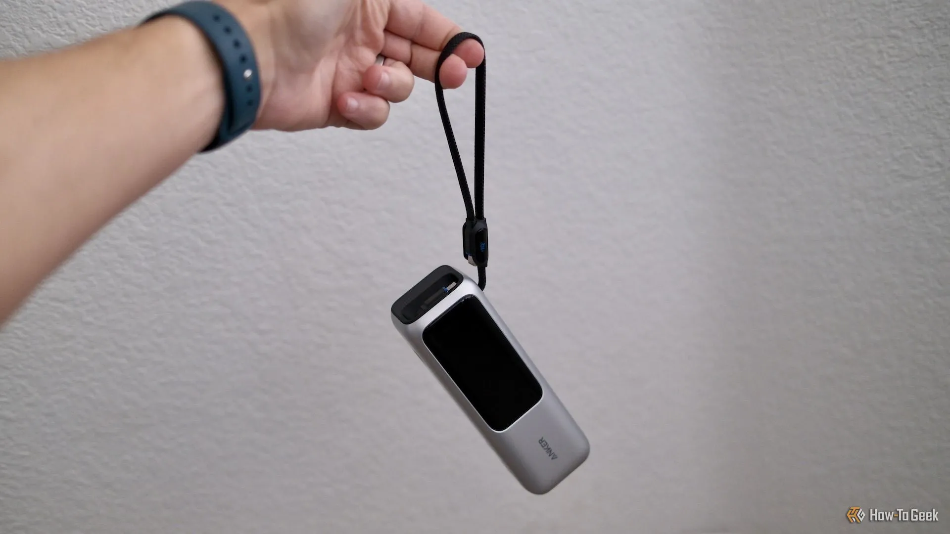 Người dùng cầm Anker Power Bank 25K bằng cáp dây đeo tích hợp, thể hiện tính năng tiện lợi khi di chuyển