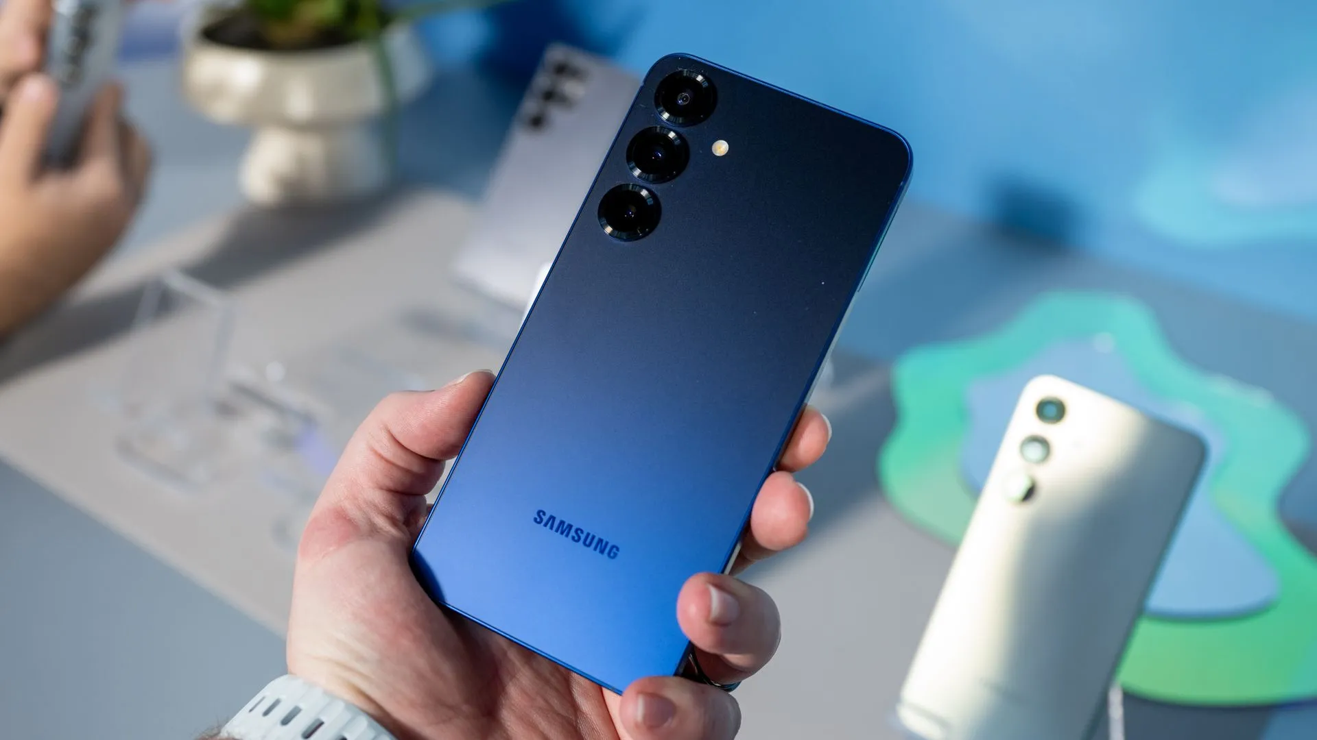 Người dùng cầm điện thoại Samsung Galaxy S25 màu Xanh Navy, tập trung vào cụm camera sau với thiết kế tinh tế và phần cứng quen thuộc.