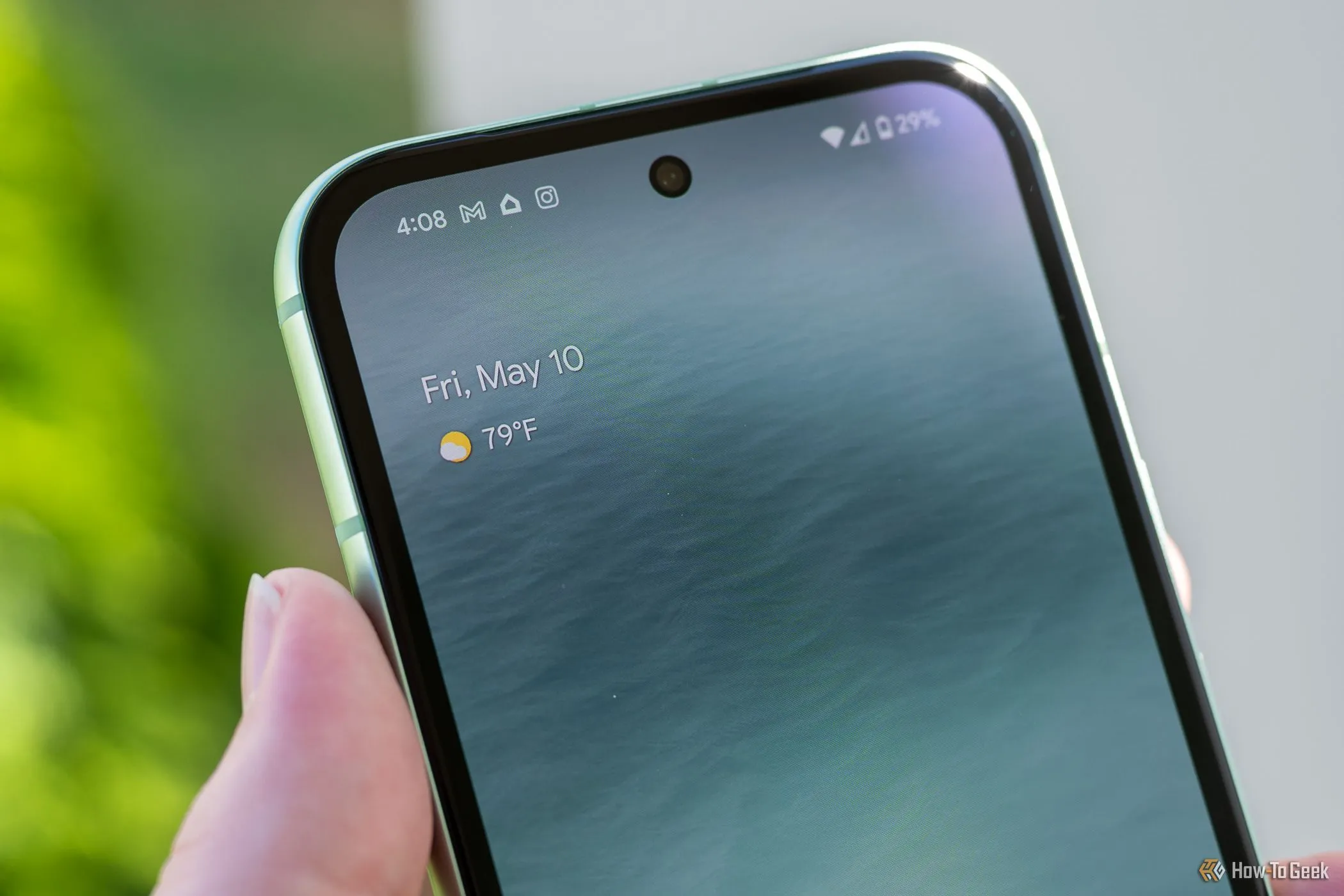 Người dùng cầm Google Pixel 8a, cho thấy camera trước dạng đục lỗ và khả năng kết nối mạng 5G của thiết bị.