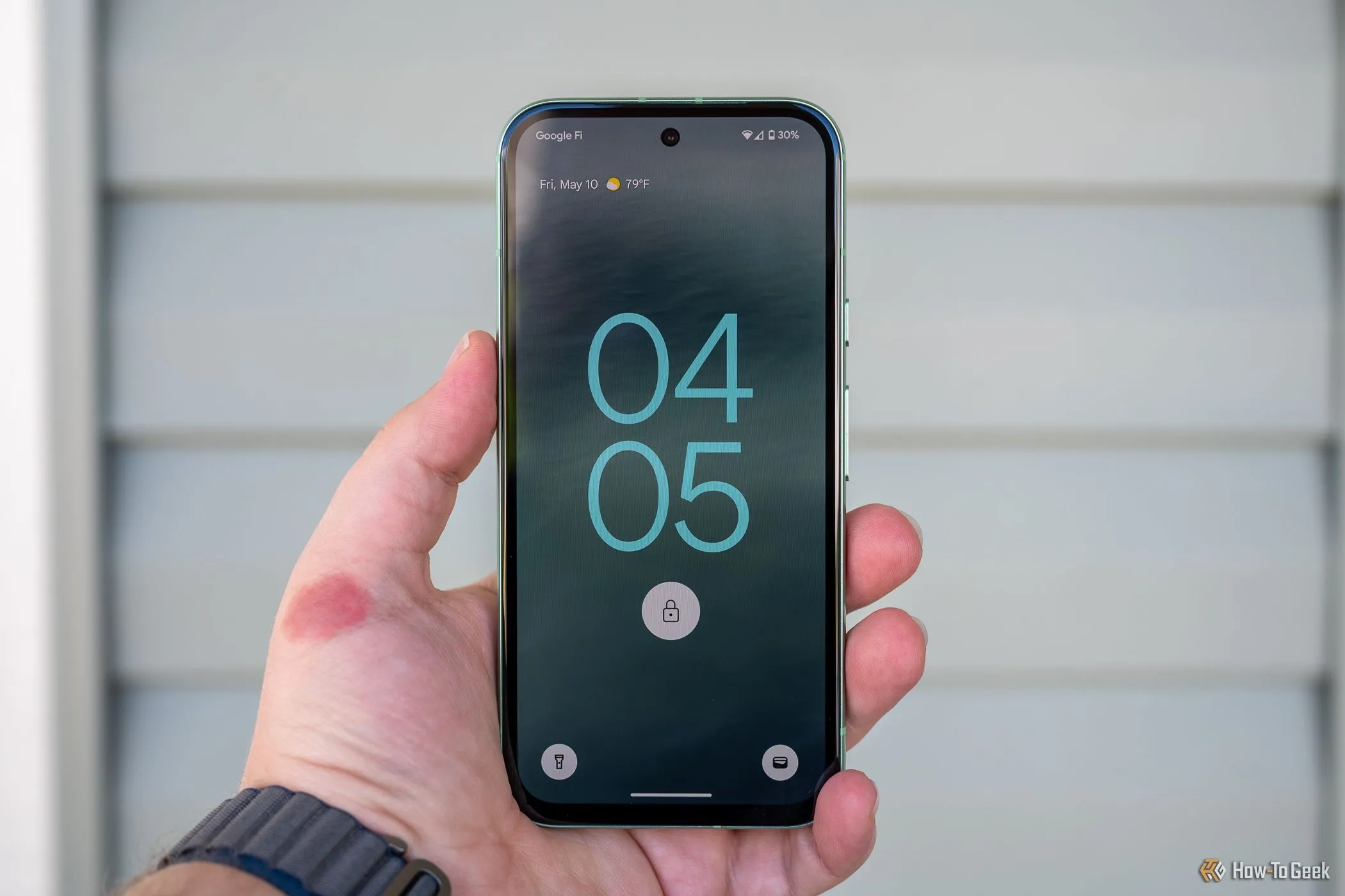 Người dùng cầm Google Pixel 8a hiển thị màn hình khóa, minh họa trải nghiệm phần mềm Android trên dòng Pixel A.