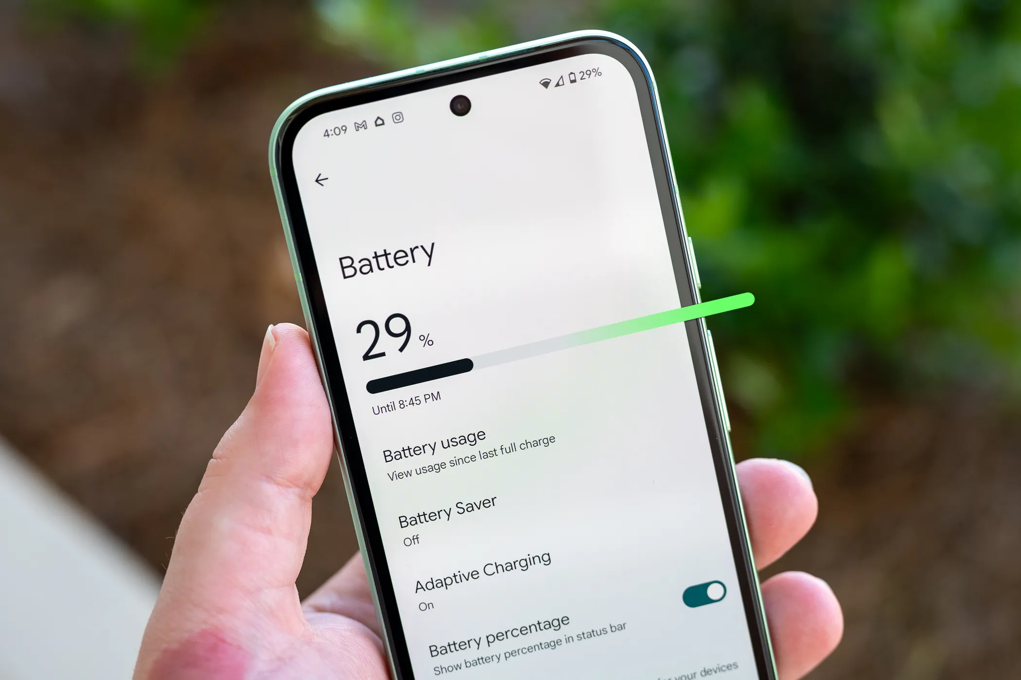 Người dùng đang cầm điện thoại Google Pixel 8a, trên màn hình hiển thị menu cài đặt Pin của Android để bật tiết kiệm pin tự động