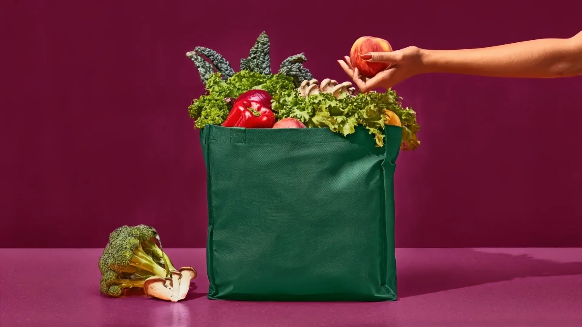 Người dùng Instacart đang bỏ trái cây vào túi xanh trên nền tím