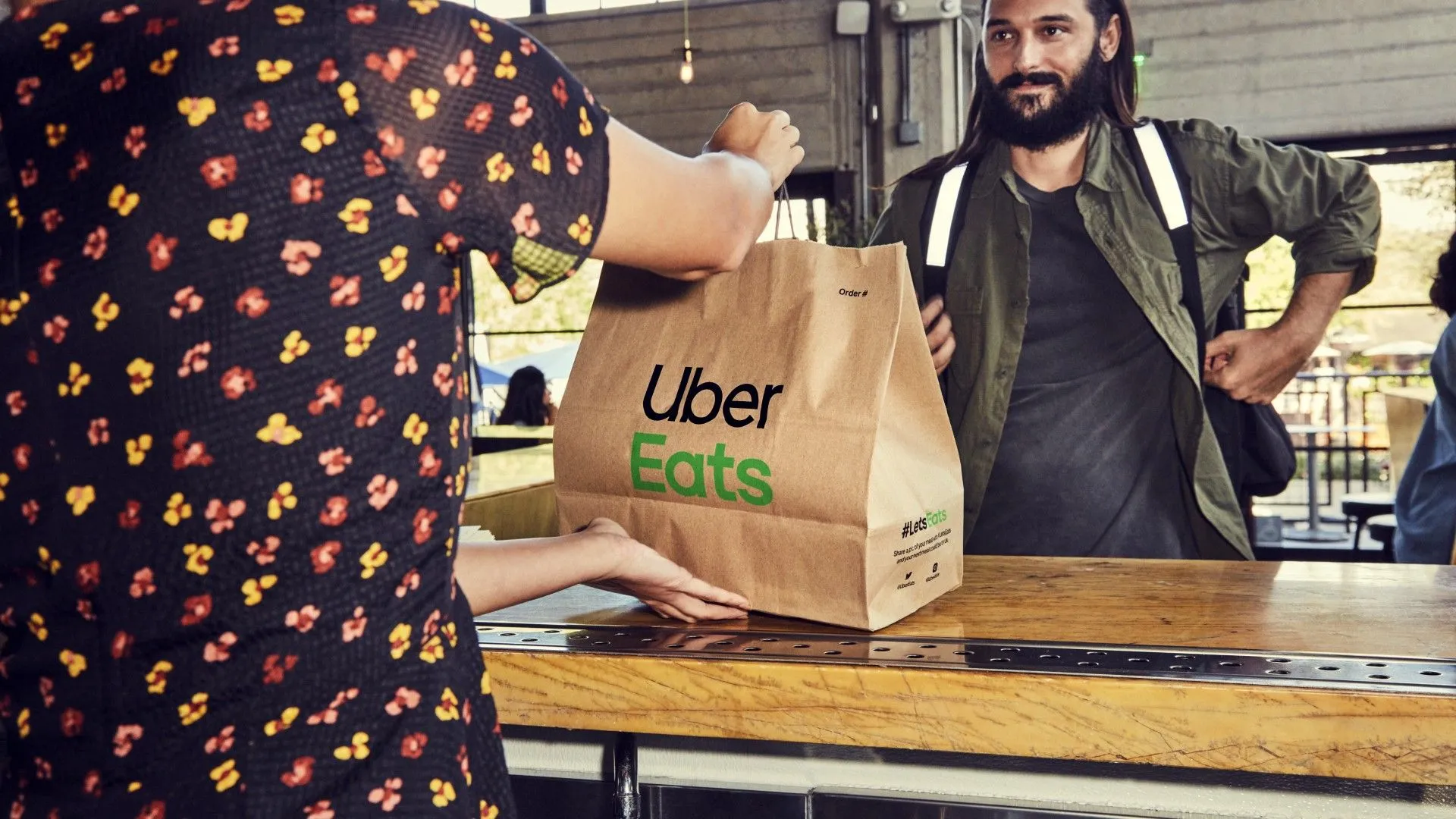 Người giao hàng Uber Eats đang nhận túi đồ ăn từ nhà hàng