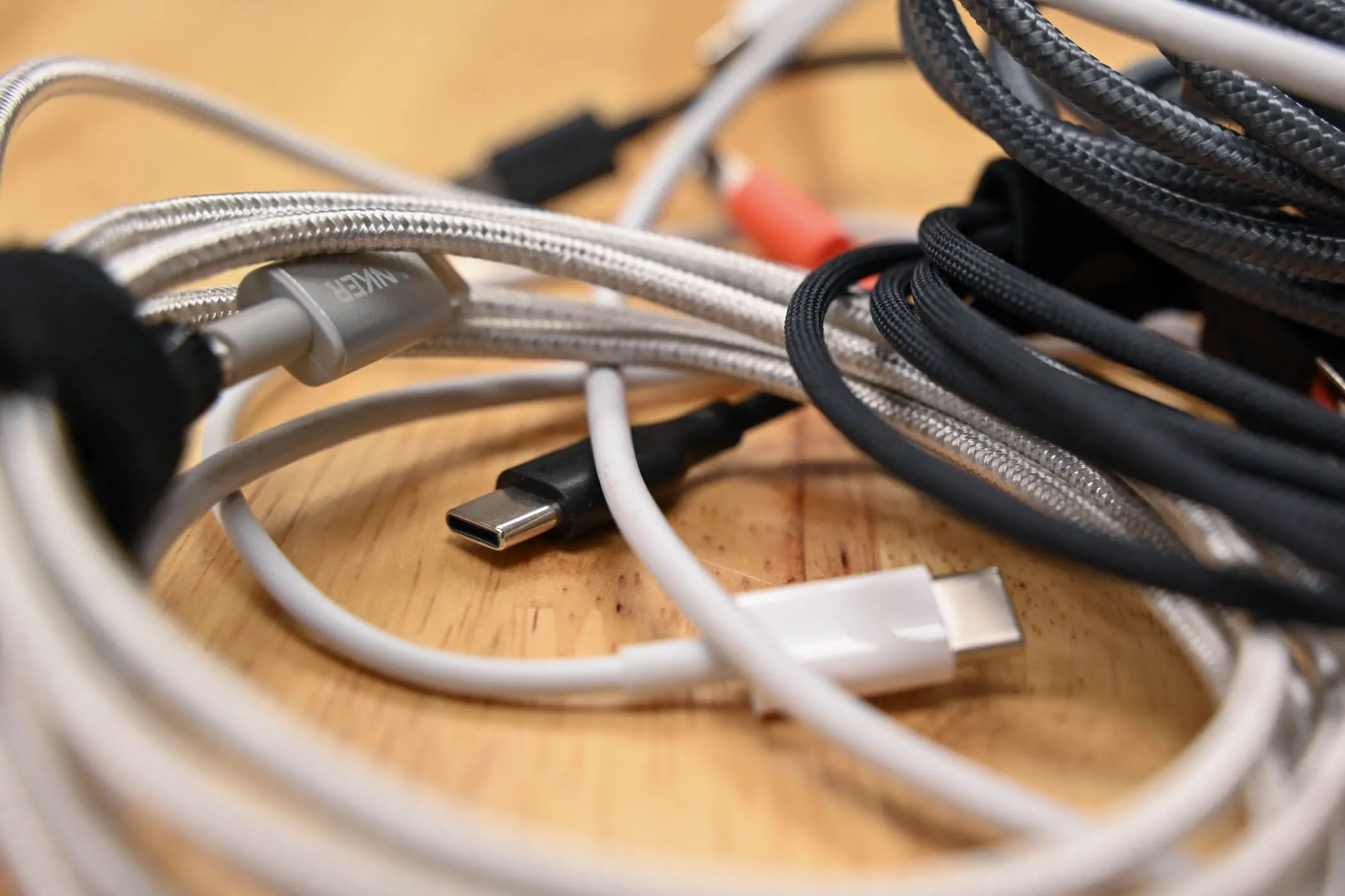 Nhiều loại cáp USB-C khác nhau trên bề mặt gỗ, cho thấy sự đa dạng của phụ kiện sạc điện thoại