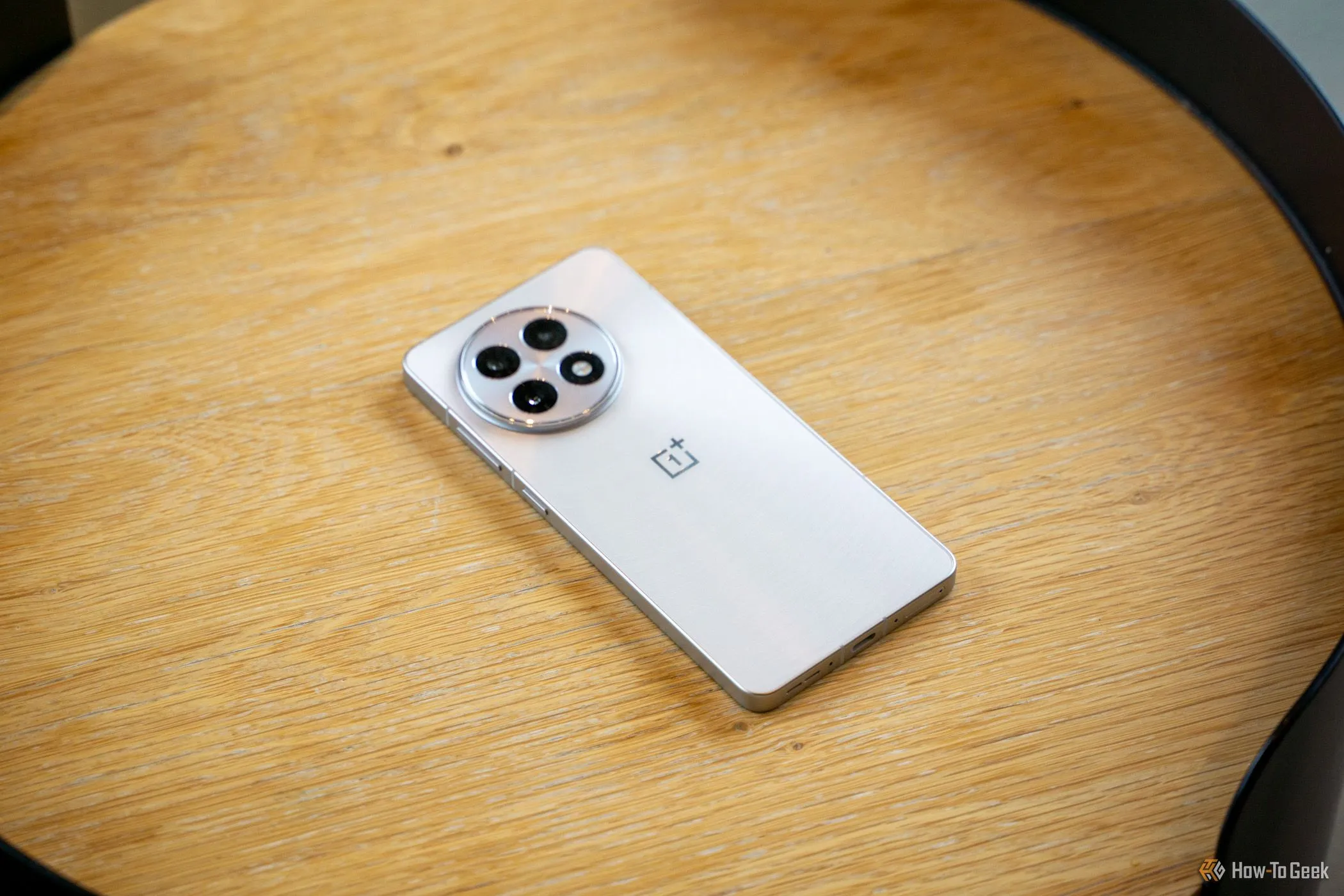 OnePlus 13R đặt úp trên bàn gỗ, khoe hệ thống camera sau