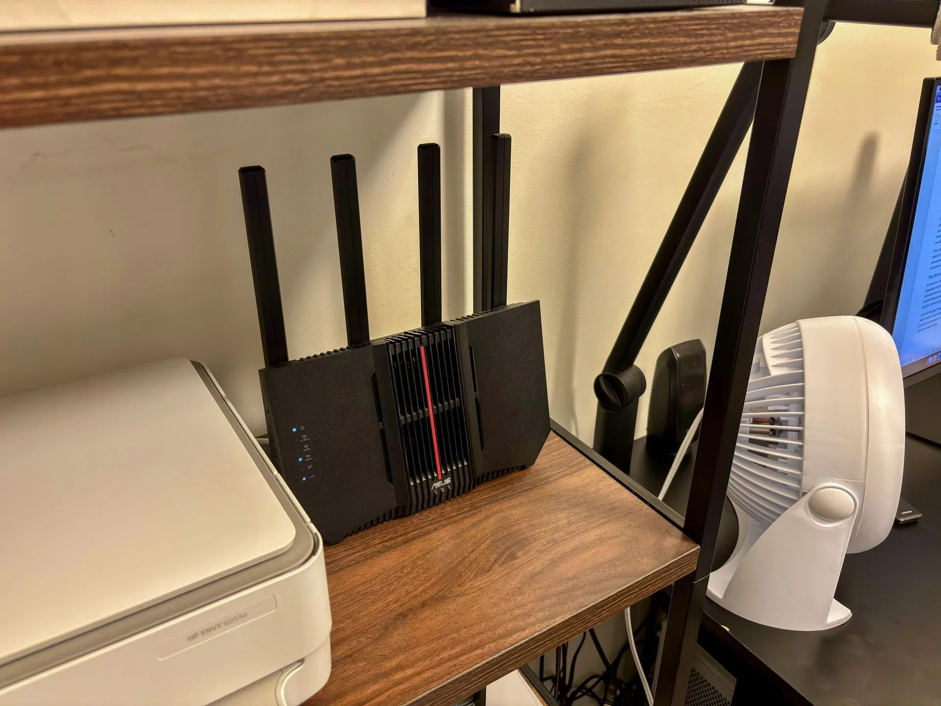 Router ASUS RT-BE92U được đặt trên kệ cùng máy in và màn hình máy tính tại khu vực văn phòng, phục vụ kết nối mạng 6 GHz