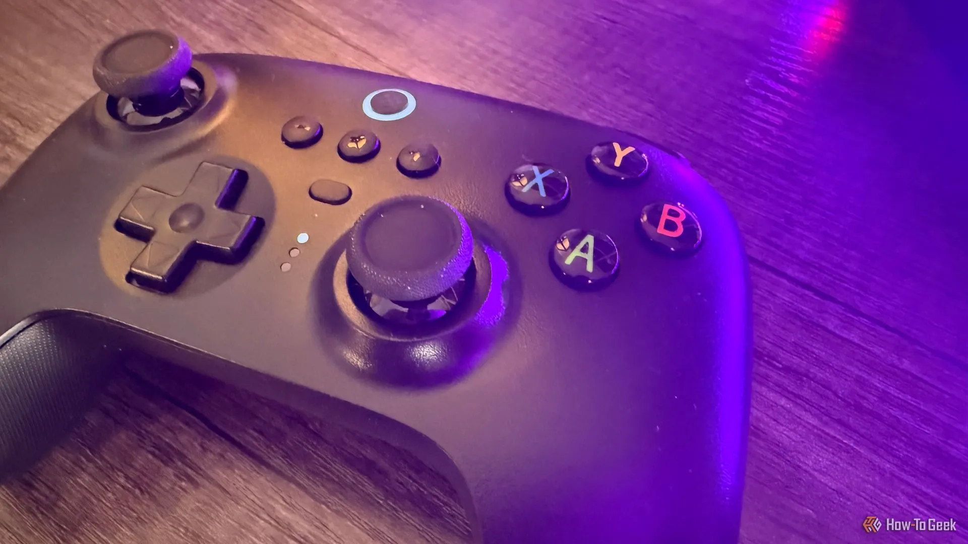 Tay cầm chơi game 8BitDo Ultimate 2.4G đặt trên bàn với ánh sáng tím, gợi ý cách tái sử dụng tay cầm console cũ cho PC.