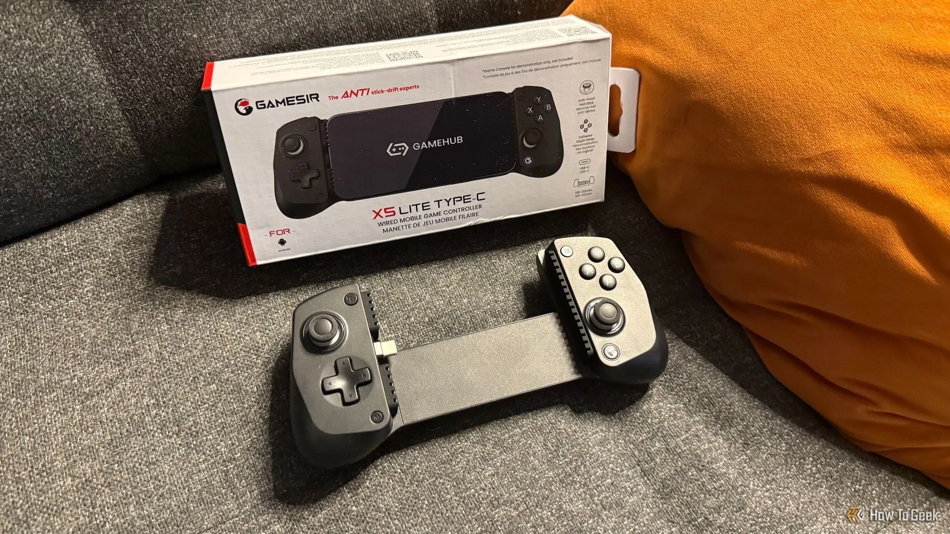 Tay cầm chơi game GameSir X5 Lite và hộp sản phẩm đặt trên ghế sofa, gợi ý về tính di động và sự tiện lợi khi sử dụng tại nhà.