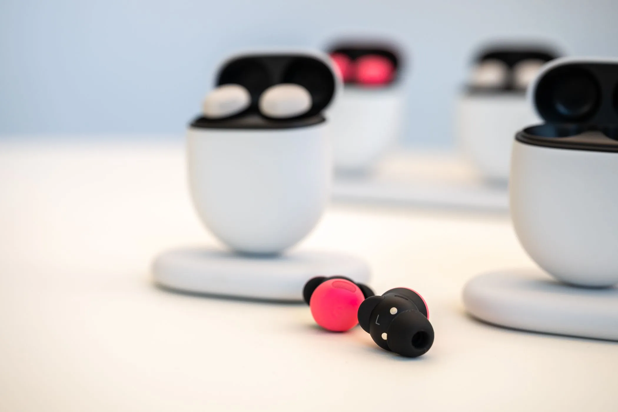 Tai nghe không dây Google Pixel Buds Pro 2 màu hồng nhạt đặt trên bàn bên ngoài hộp sạc.