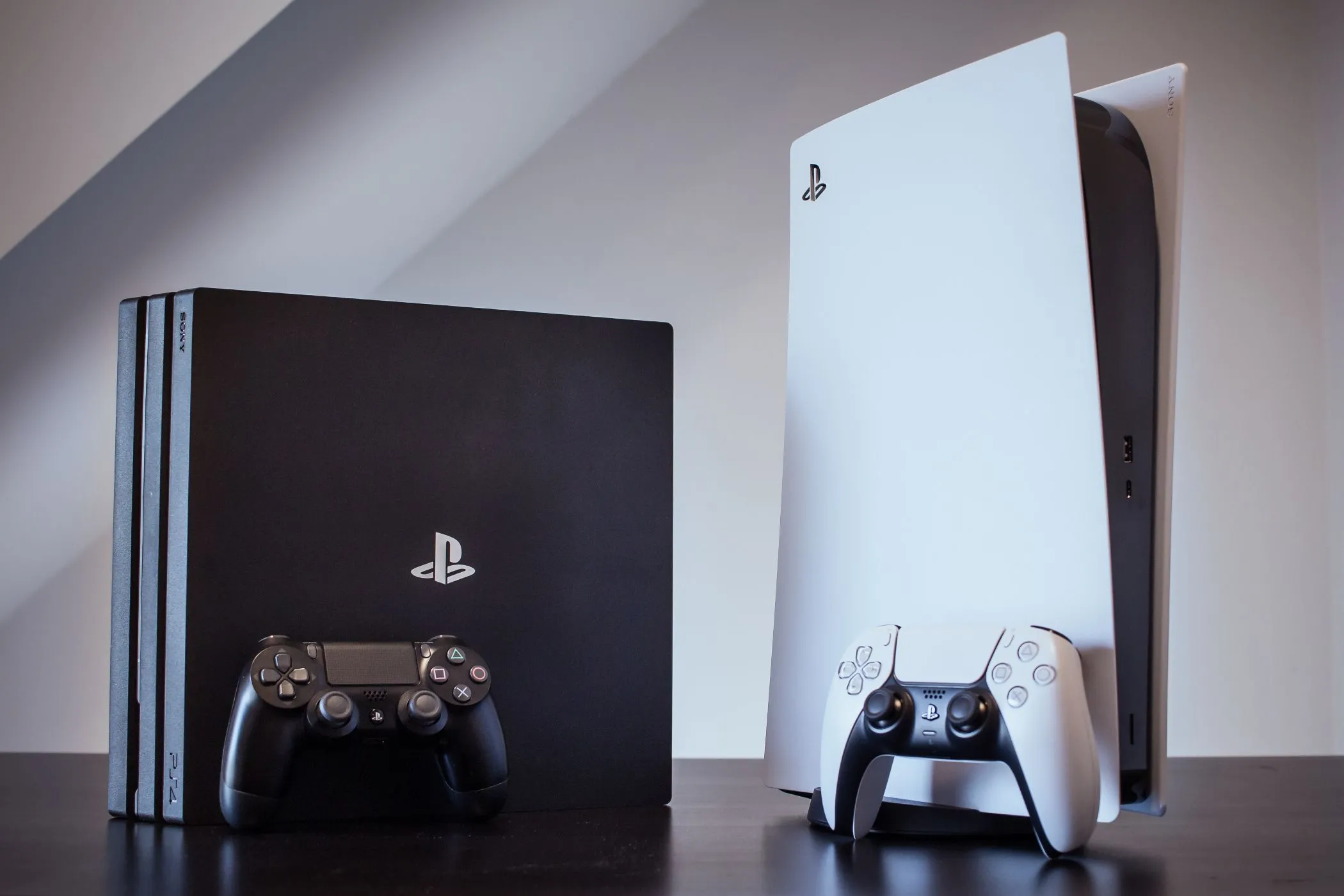 Máy chơi game PS4 Pro và PS5 đặt cạnh nhau, minh họa sự tương đồng về đồ họa giữa các thế hệ gần đây