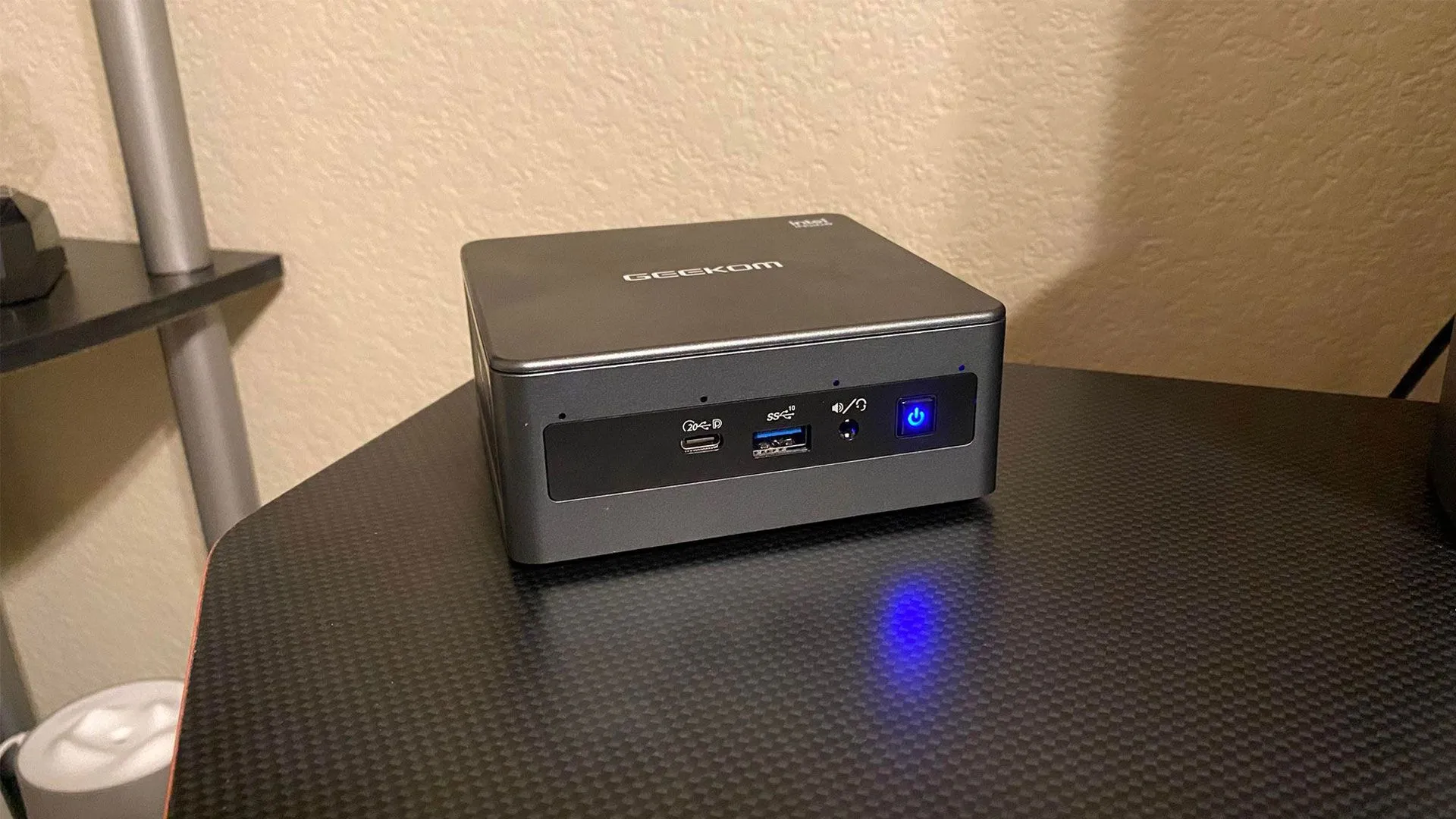Máy tính Mini PC GEEKOM Mini IT11 đặt trên mặt bàn màu đen, minh họa khả năng thay thế PC để bàn cho nhiều tác vụ khác nhau.