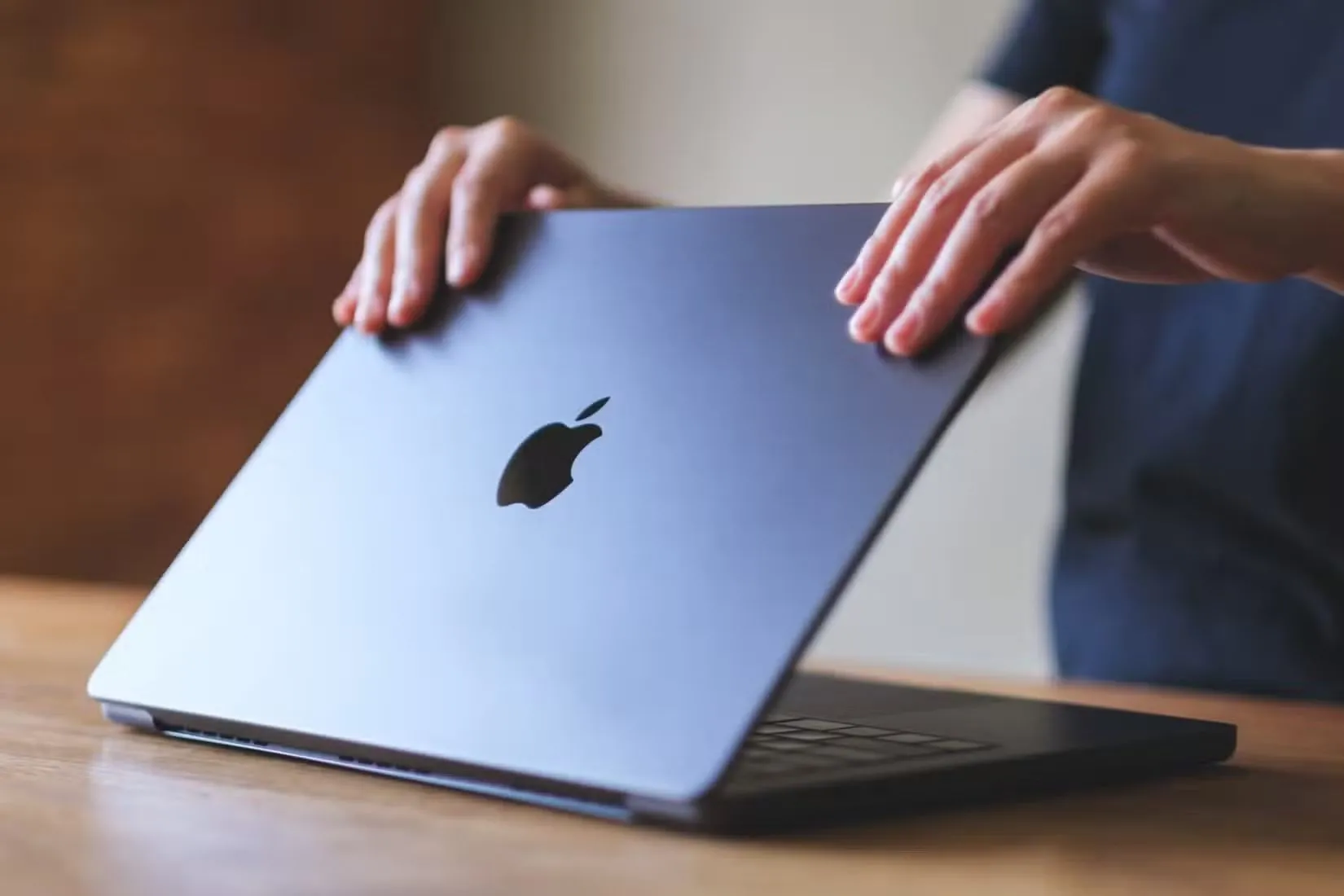 Một người đang mở chiếc MacBook, thể hiện sự tiện lợi và tức thì khi tiếp tục làm việc trên macOS sau khi đóng nắp máy.