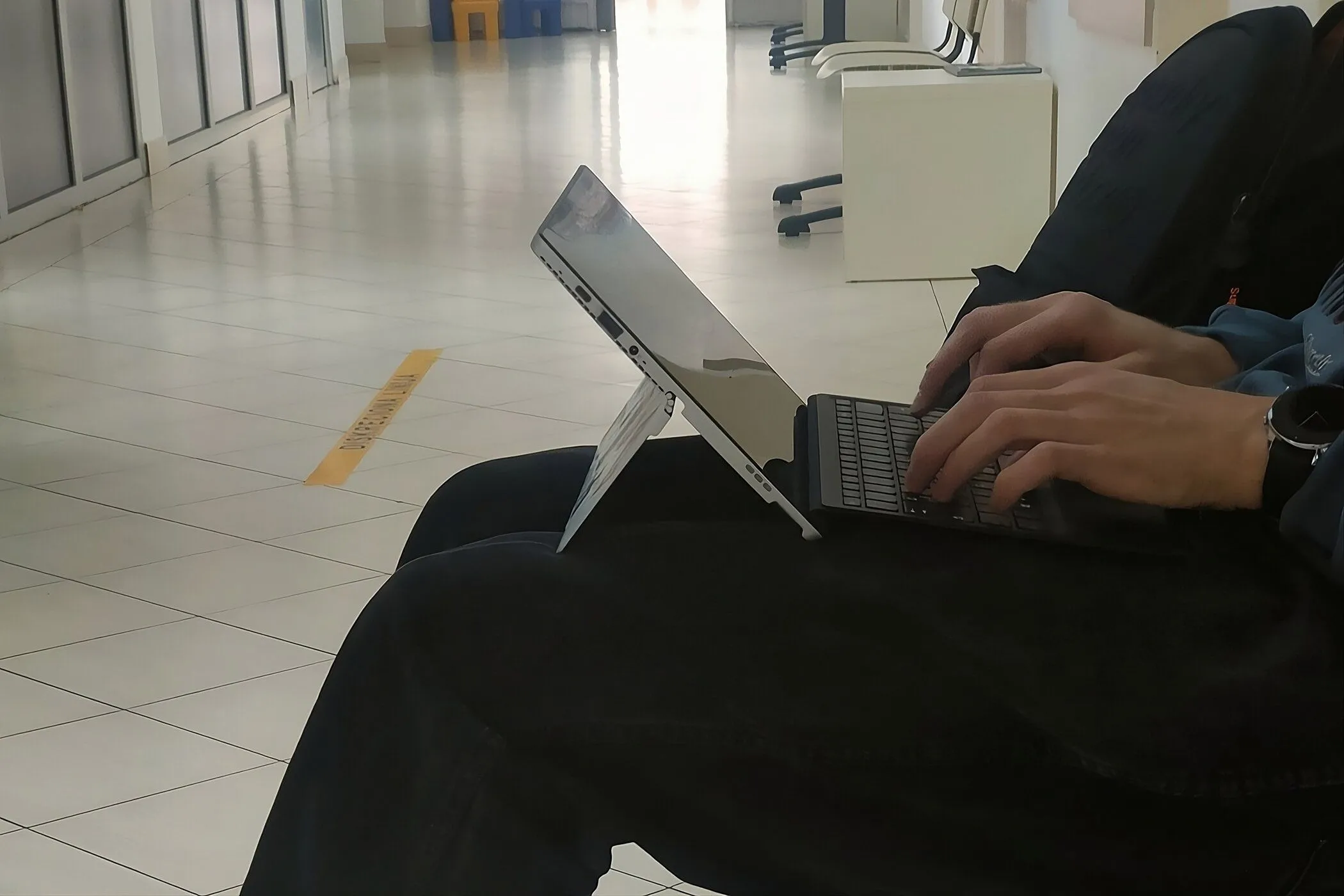 Người dùng gõ phím trên laptop 2-in-1 đặt trên đùi
